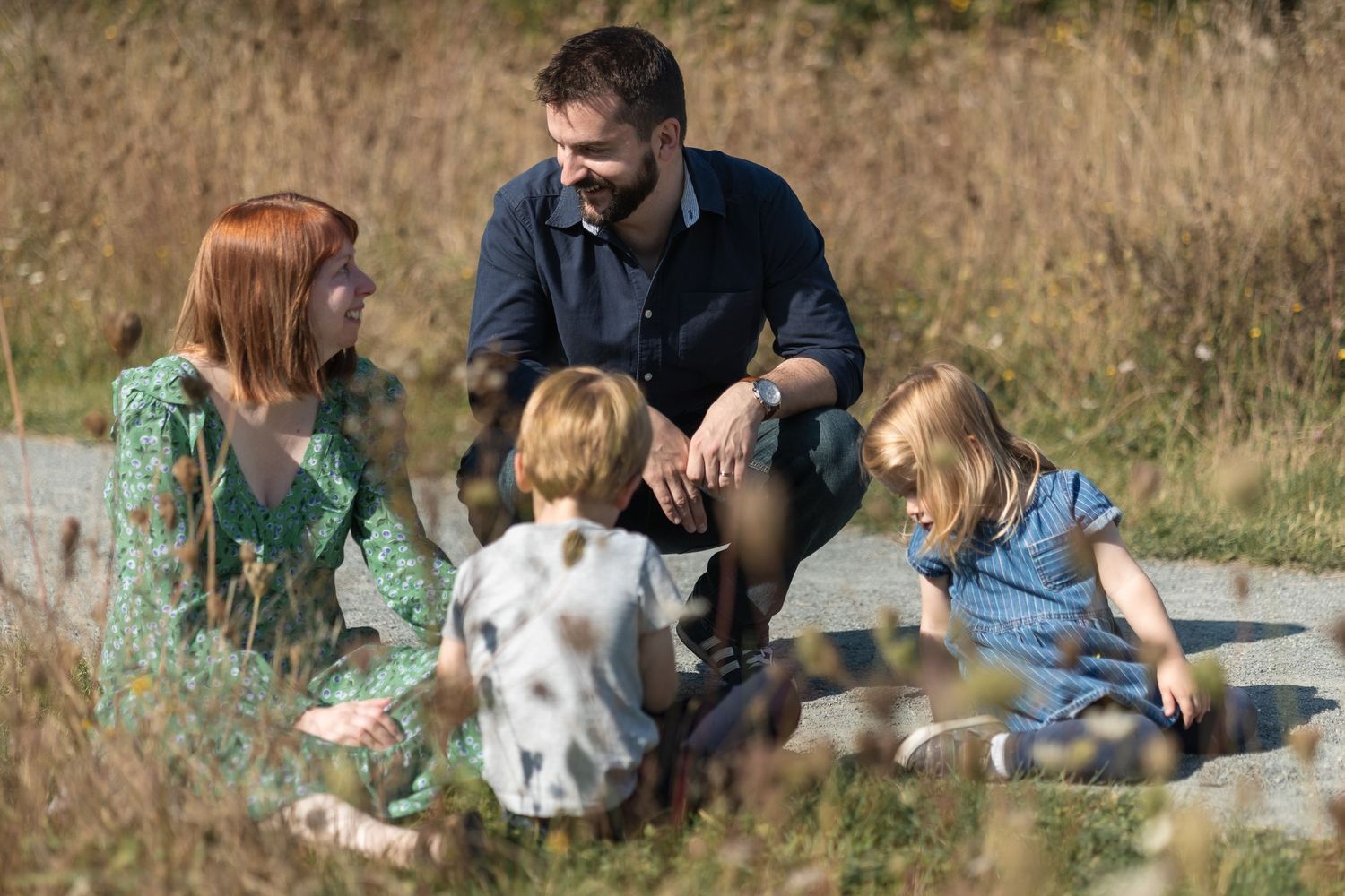 Family relax together on a sunny autumn afternoon, sitting on a picnic blanket on the floor, laughing and chatting together