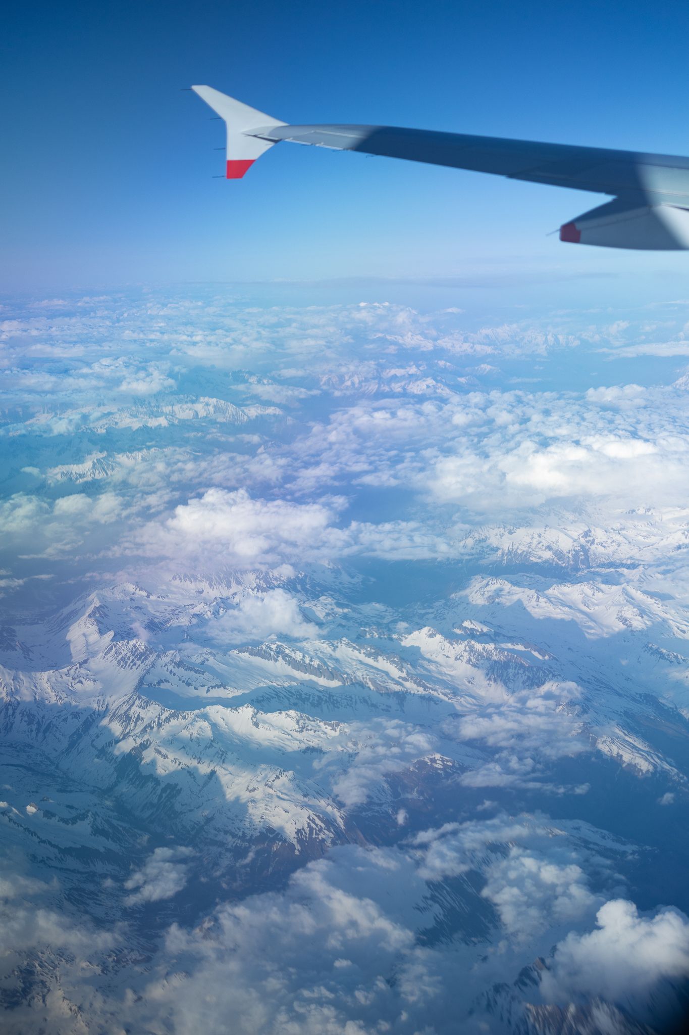 View of a plane wing flying over the Alps.