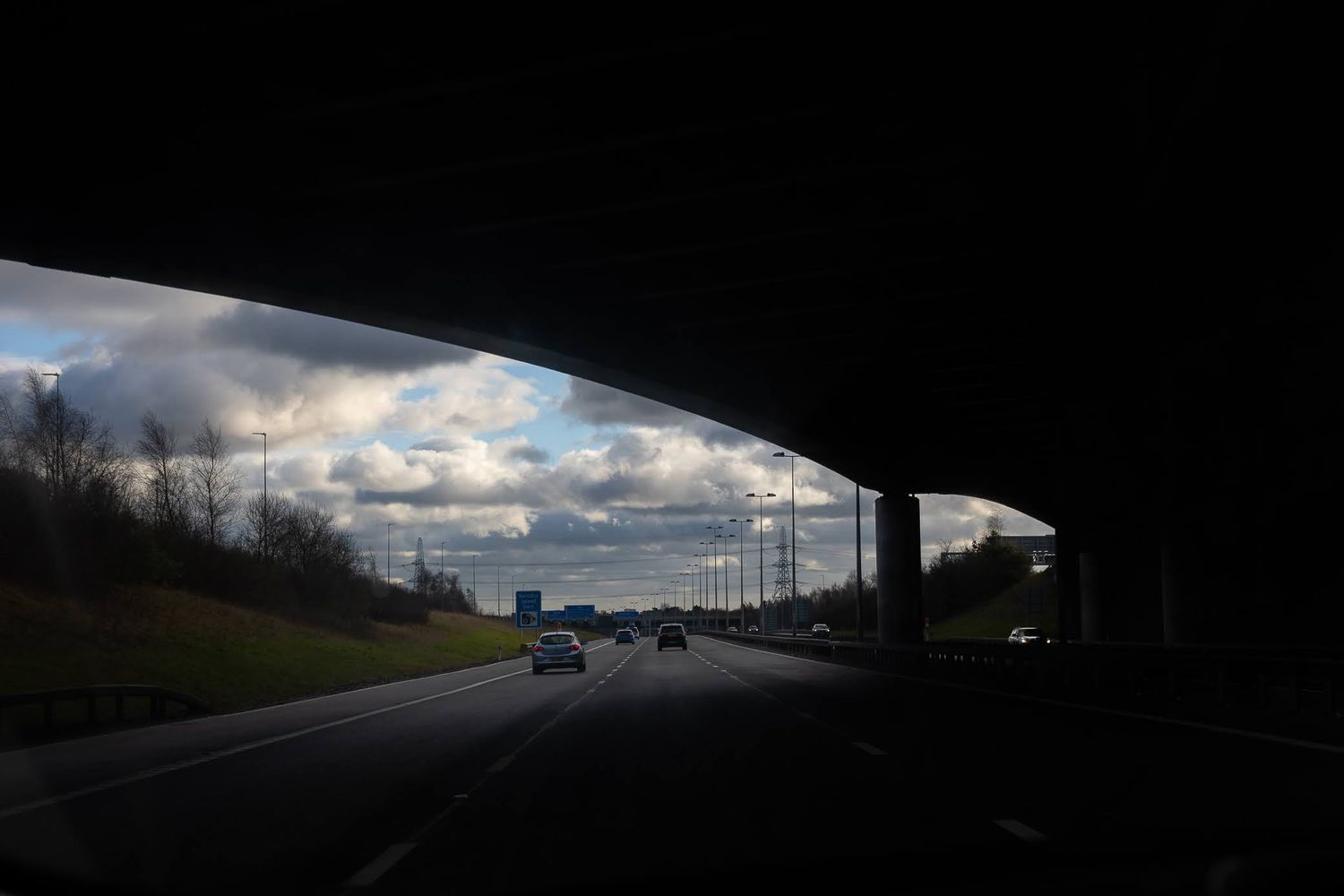 Geometric shapes created by a flyover on the motorway, drawing attention to the clouds and dramatic sky in the distance.