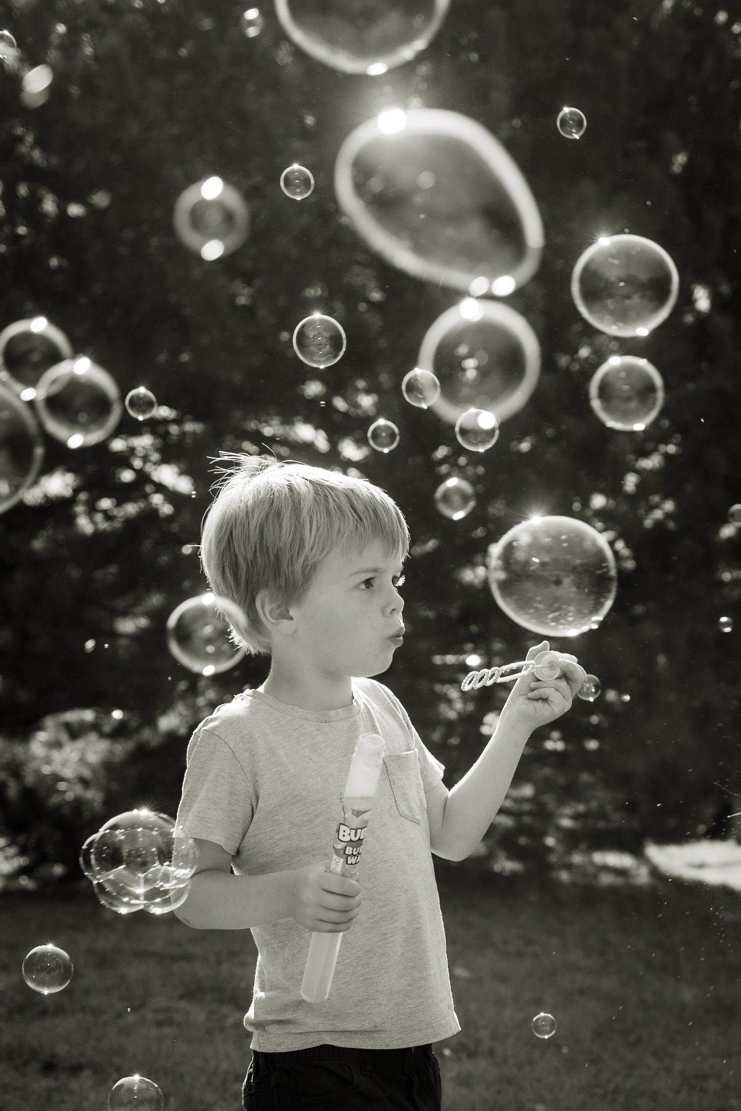 Black and white image of a young boy blowing bubbles on a family shoot.