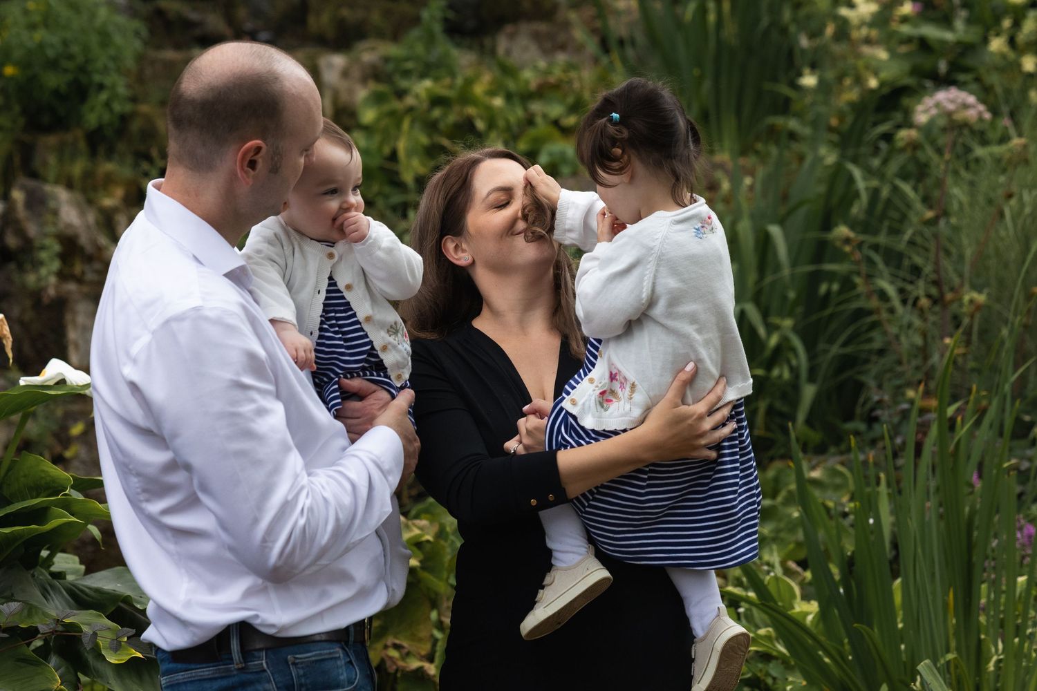A family of 4 laughing and smiling together during a family shoot in Regents park, London.