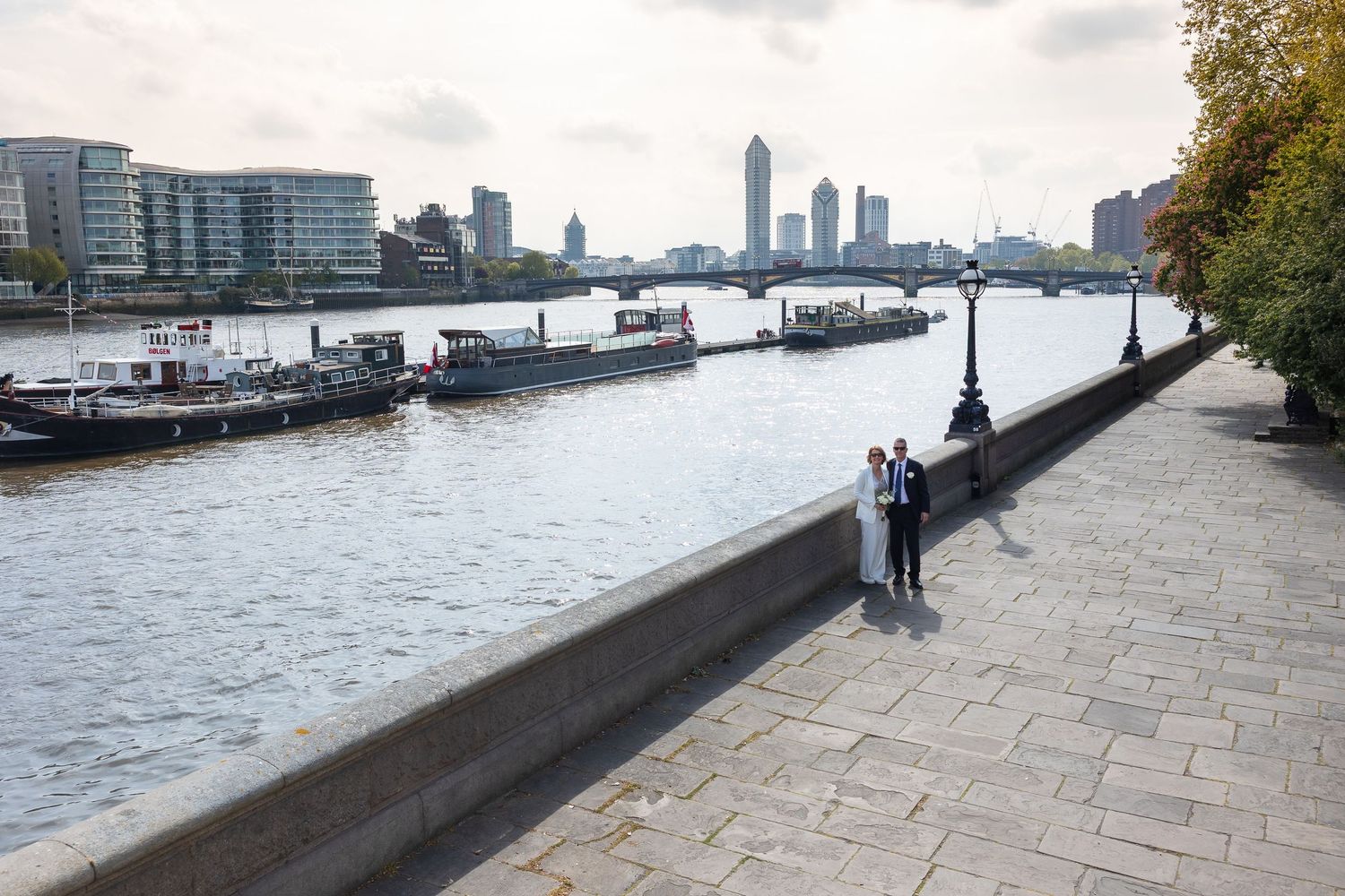 Wide angle photo of the bride and groom with the Thames behind them, just off the Albert Bridge in South Kensington.