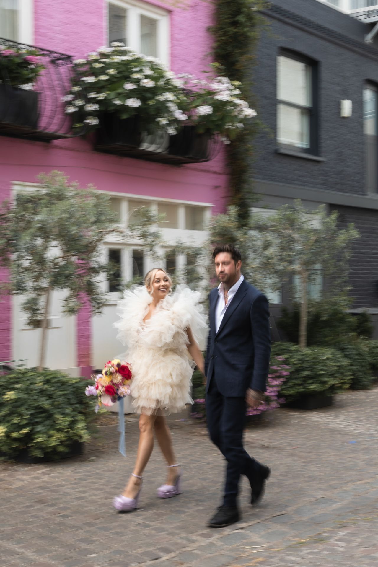Stylish Couple walk past colourful houses in Notting Hill after their elopement.
