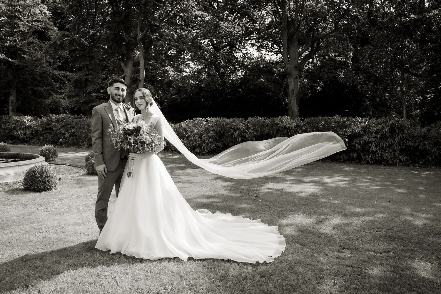 Black and white couple portrait. The wind has caught the brides veil and it is flowing in the air on the side of her.