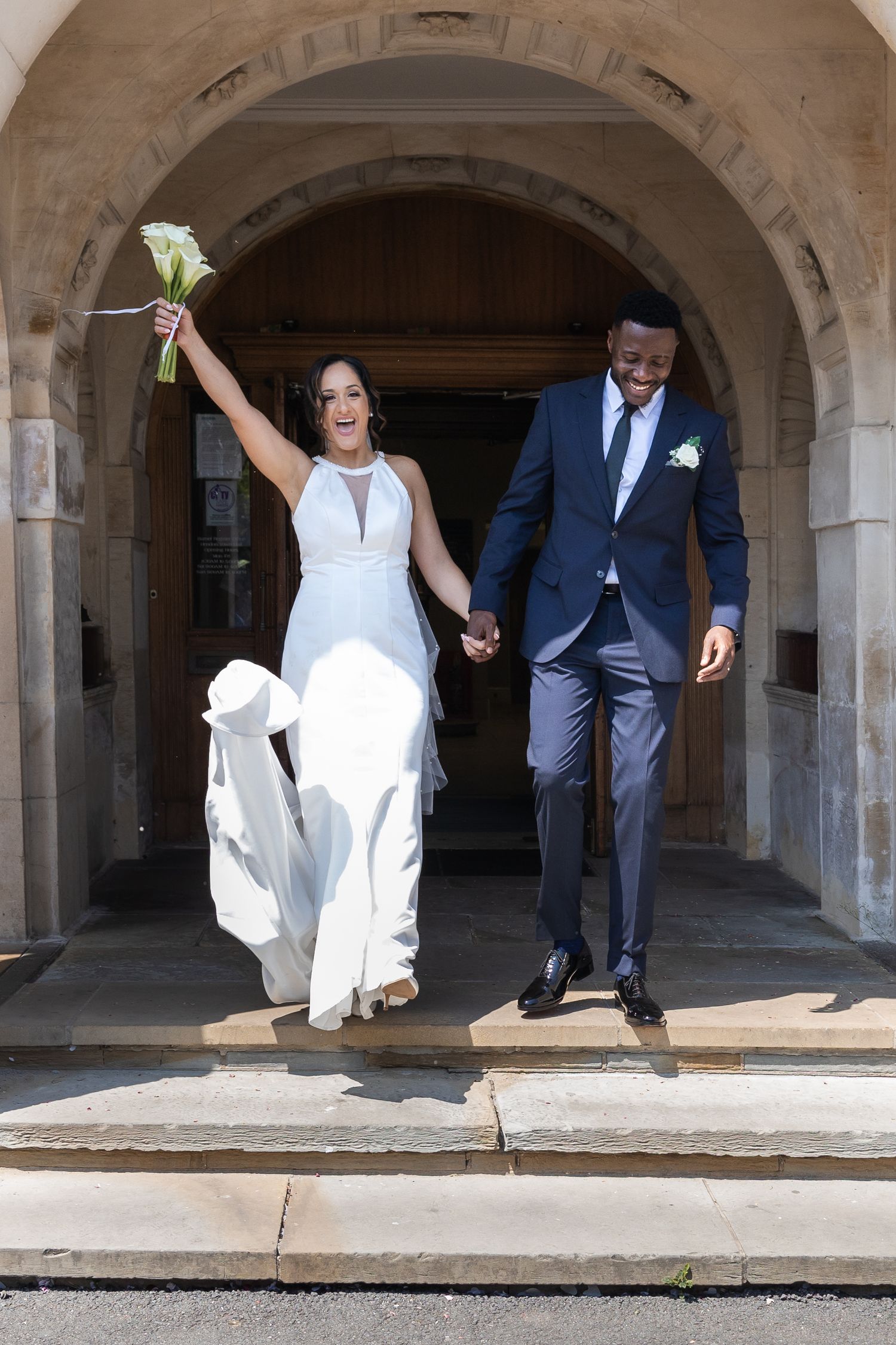 That newly wed feeling. The couple walk out of the ceremony together as husband and wife. Bride throws her hand in the air!