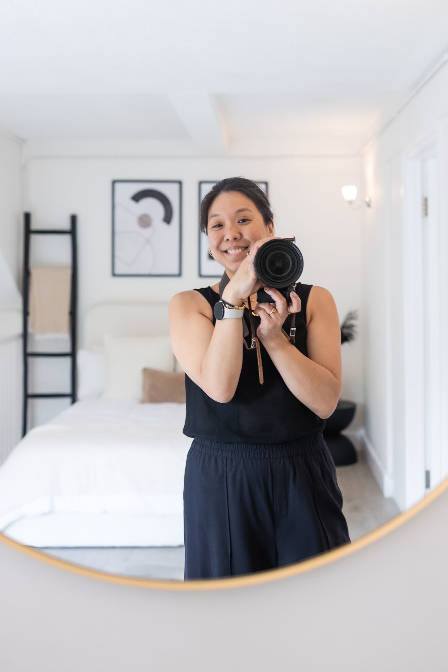Candid image of me, a reflection in the mirror, holding my camera and smiling in a relaxed way.