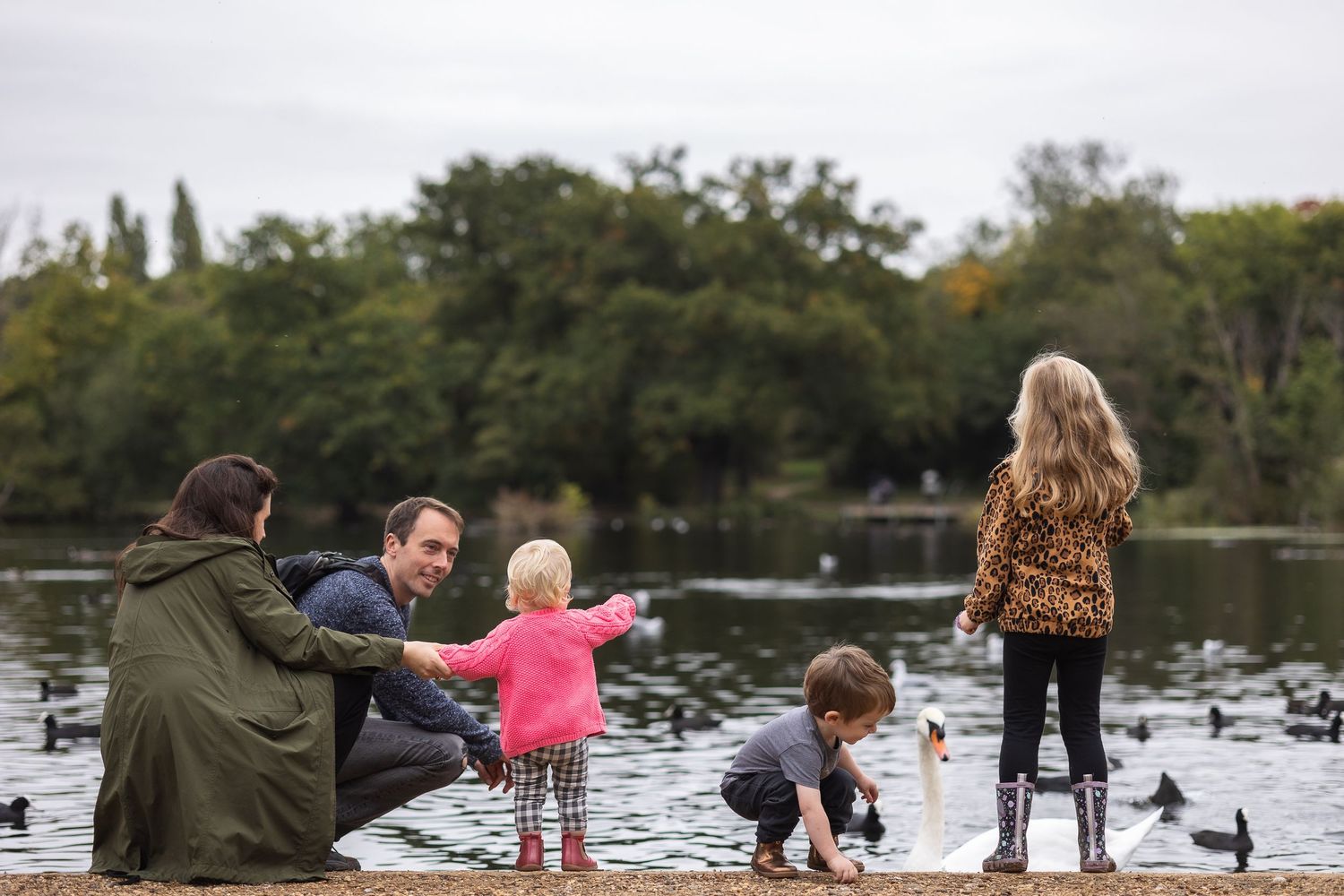 Family of 5 standing infront of lake in Higham Park feeding the ducks.