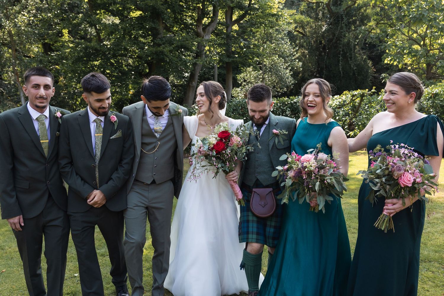 A relaxed and natural image of the bridal party, including the bride, bridesmaids, groom and groomsmen.