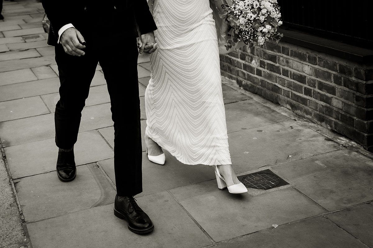 Black and white image of bride and groom walking along the streets of Chelsea, South West London