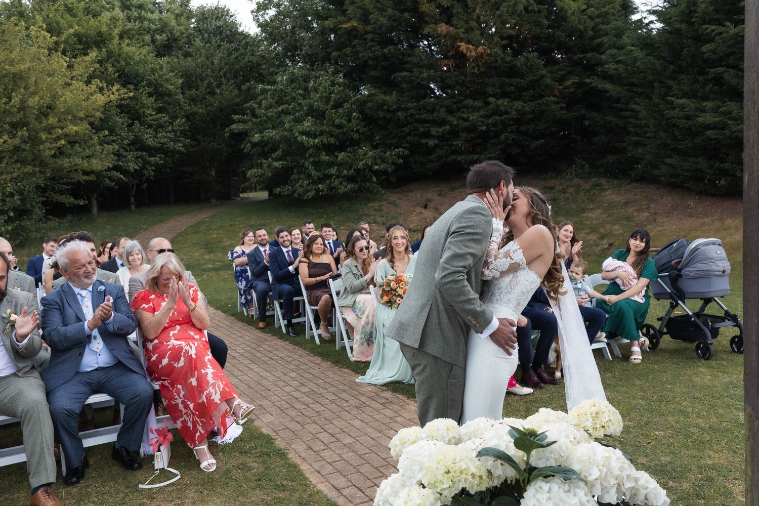 Bride and groom share first kiss at outdoor ceremony in Hertfordshire.