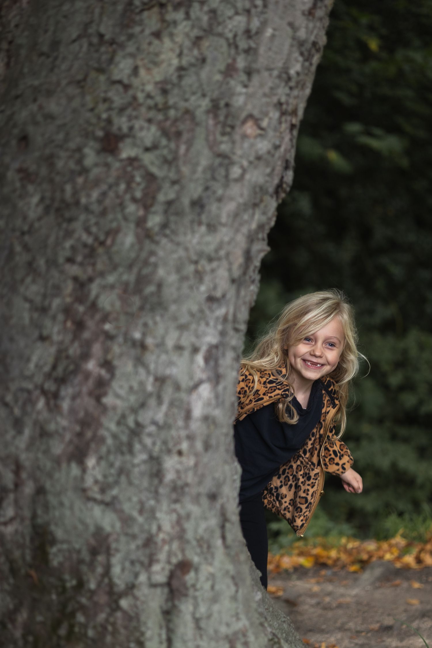 Playing peek a boo with the family whilst on an outdoor shoot. Girl is poking her head from behind a tree.