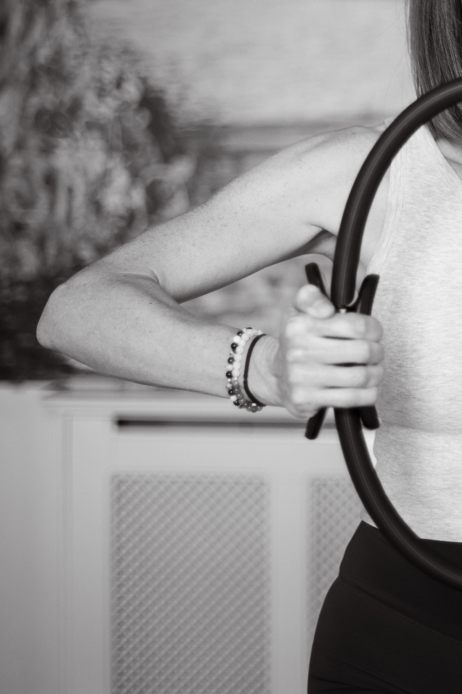 Black and white photo of a woman holding a Pilates magic circle ring during a workout session.
