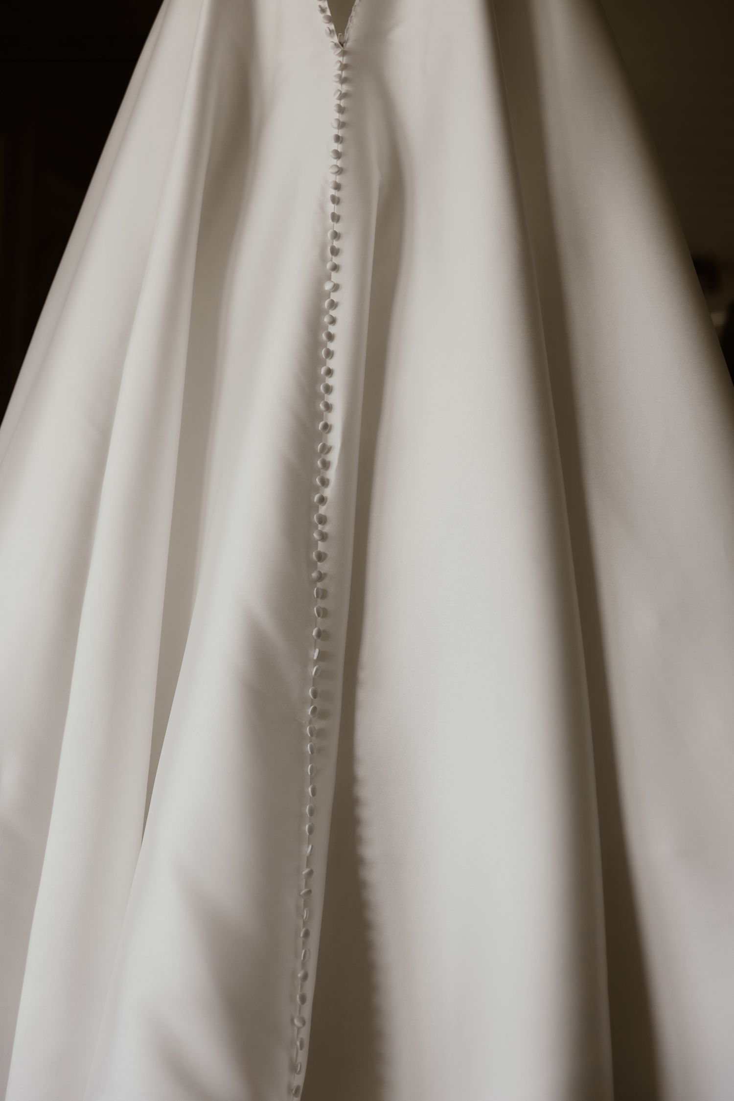 Close-up detail of buttons and seams on a white wedding dress.