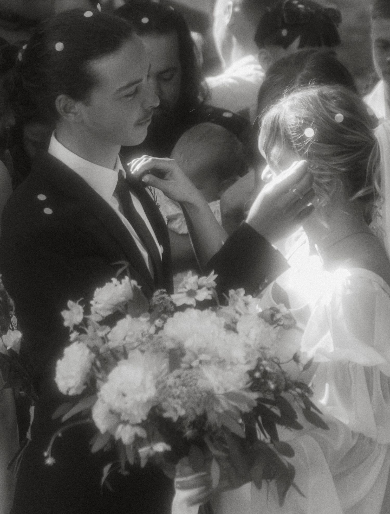 Black and white wedding photograph with an elegant bouquet of white flowers in soft focus romantic style.