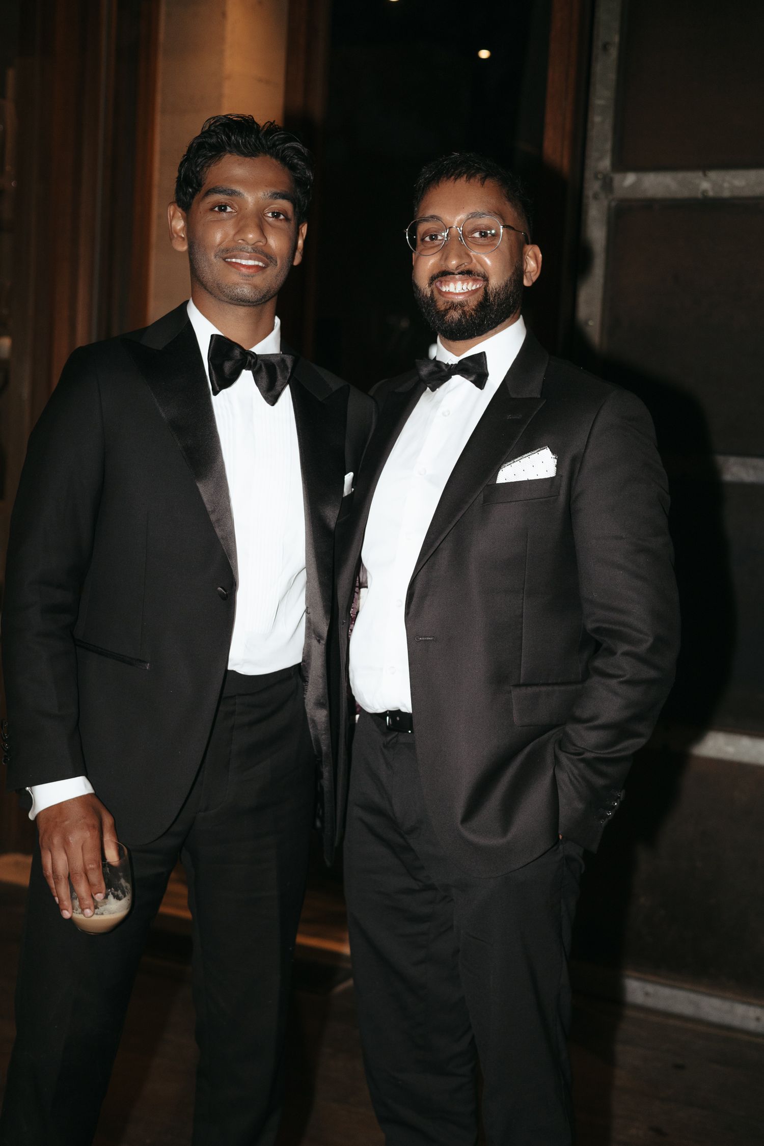 Guests in black tie tuxedos share laughs at an evening celebration.