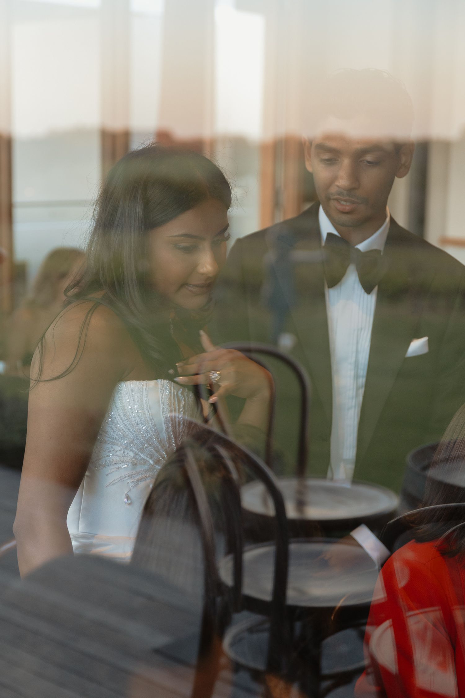 Elegant reception dinner scene viewed through reflective glass windows.