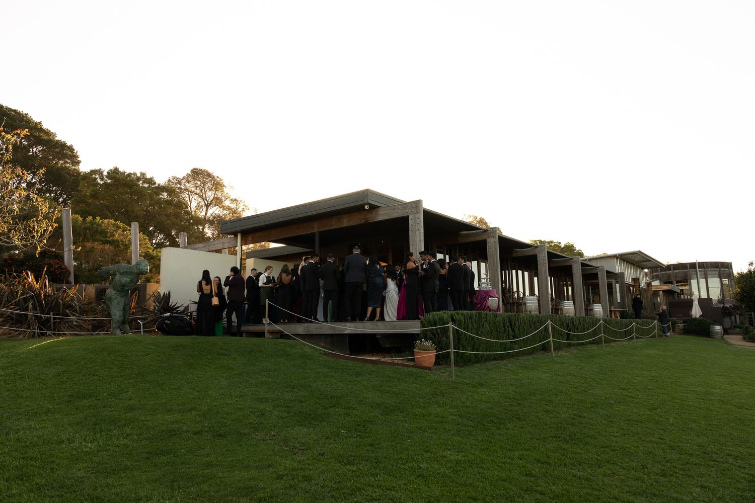 Panoramic view of outdoor event space with tents and buildings spread across a grassy hillside at dusk.