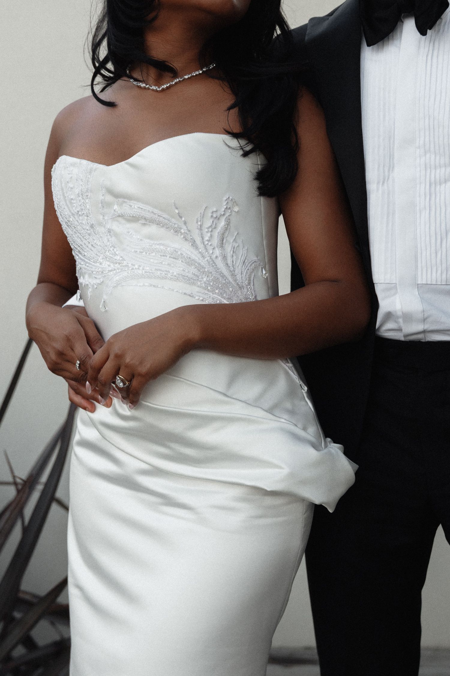 Close-up detail shots of a white strapless wedding dress bodice and midsection with delicate beading and ruching details.
