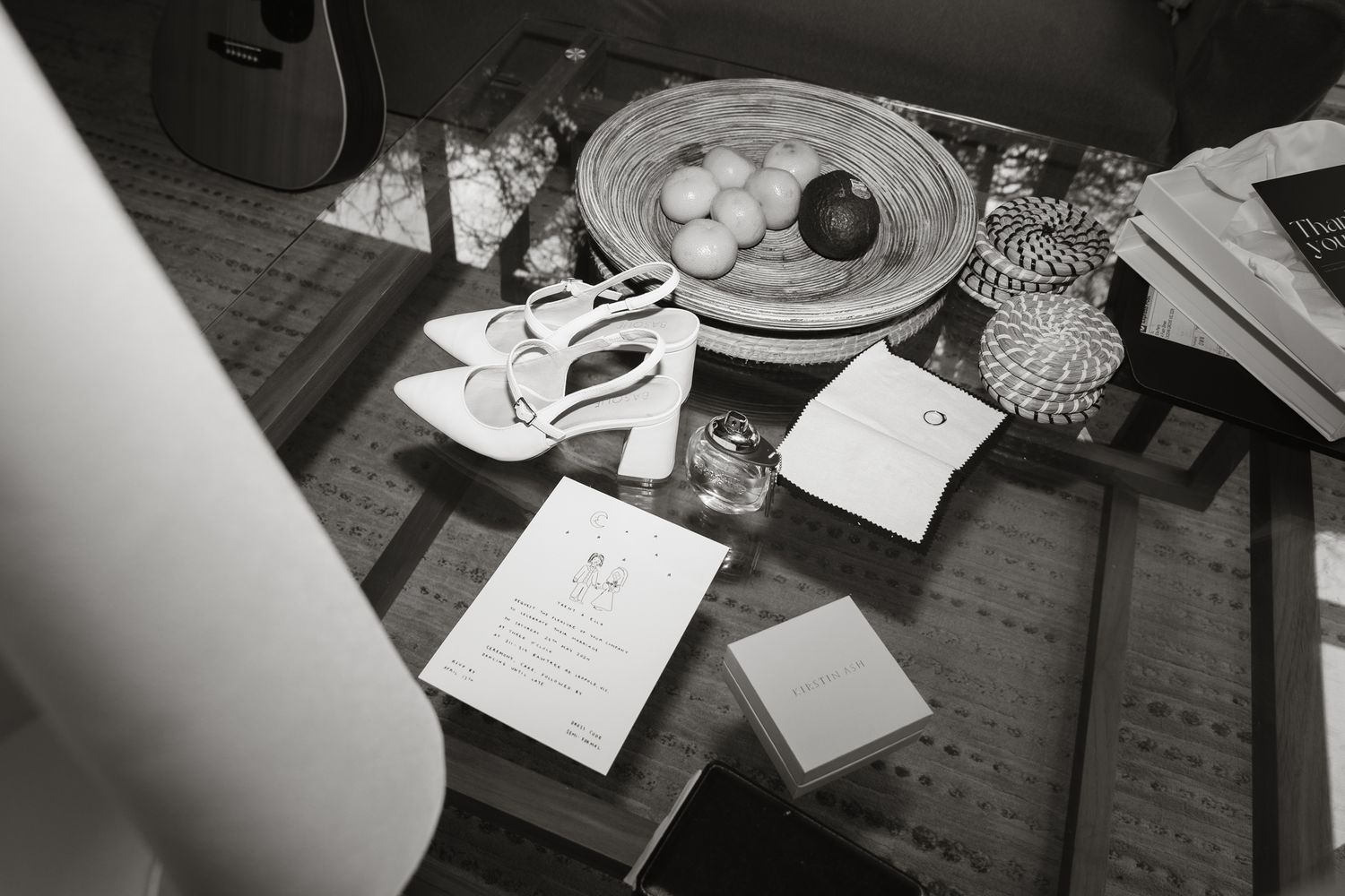 A black and white overhead view of a table with papers, eggs on a plate, and drinking glasses scattered about.
