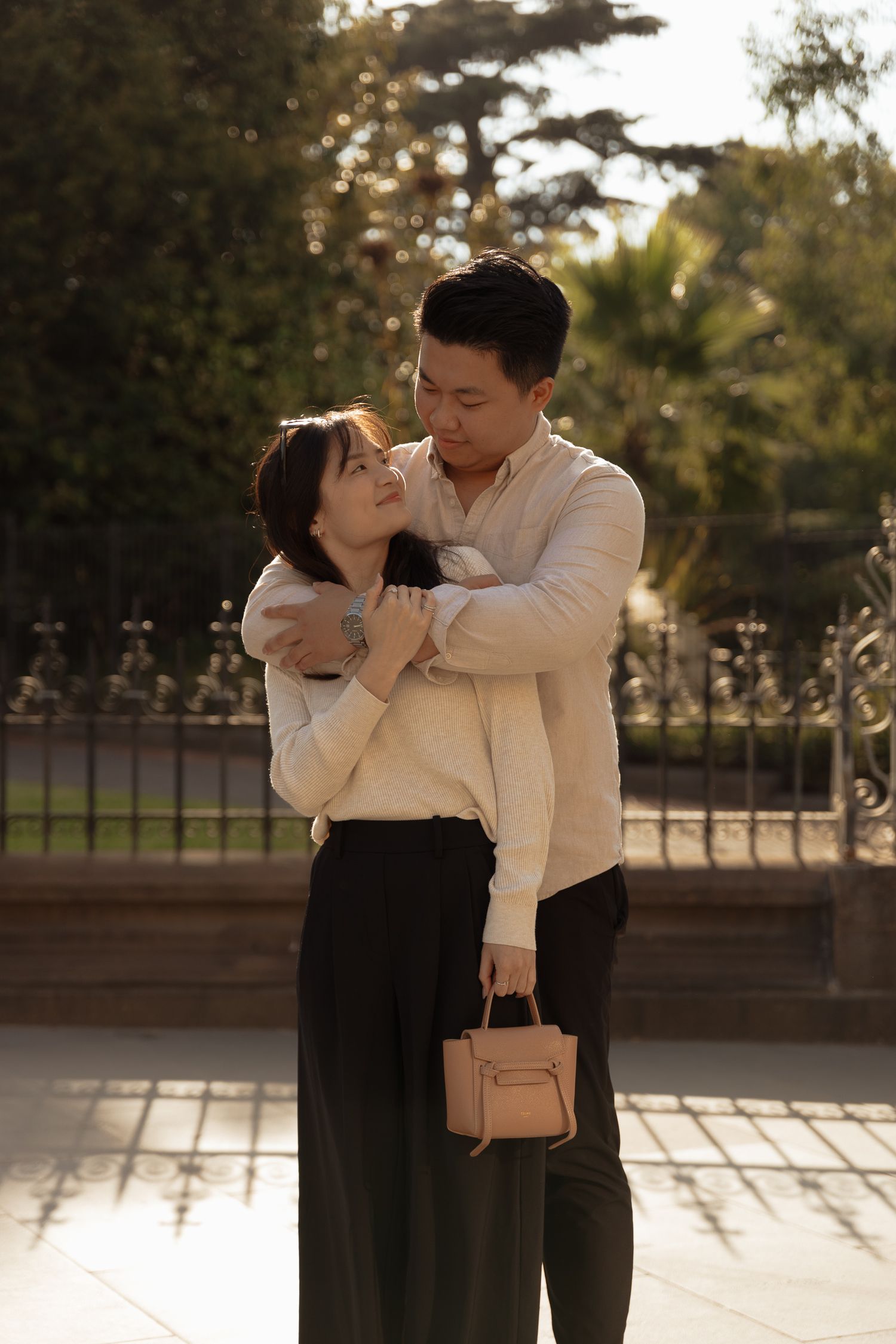 A romantic couple shares tender moments together in a park during golden hour lighting.
