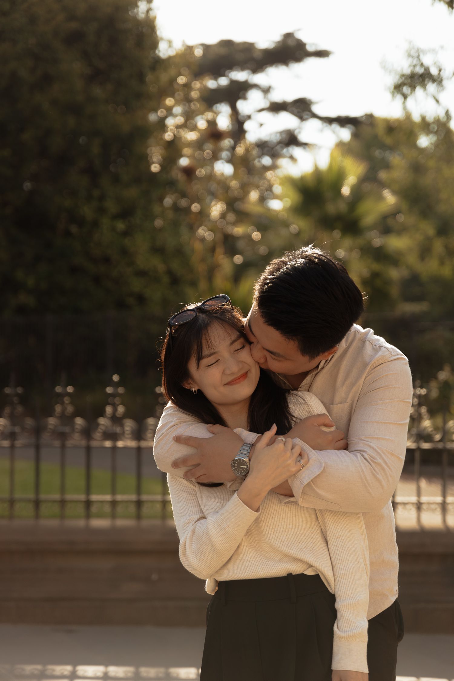A romantic embrace captured in golden sunlight against a park background.