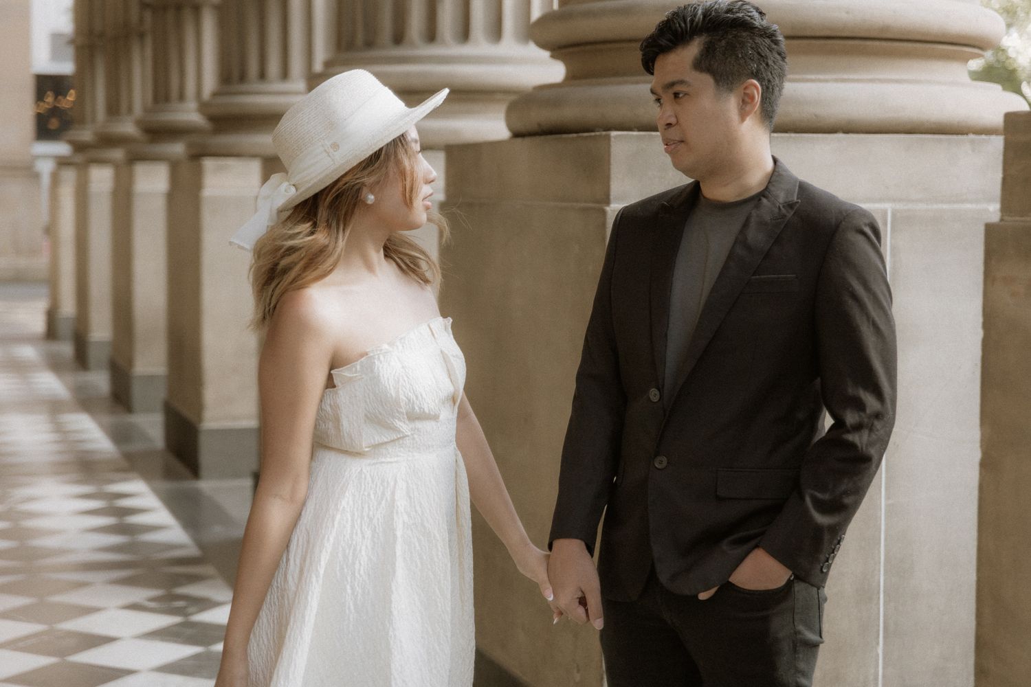 A couple poses in elegant Melbourne State Library with natural lighting.