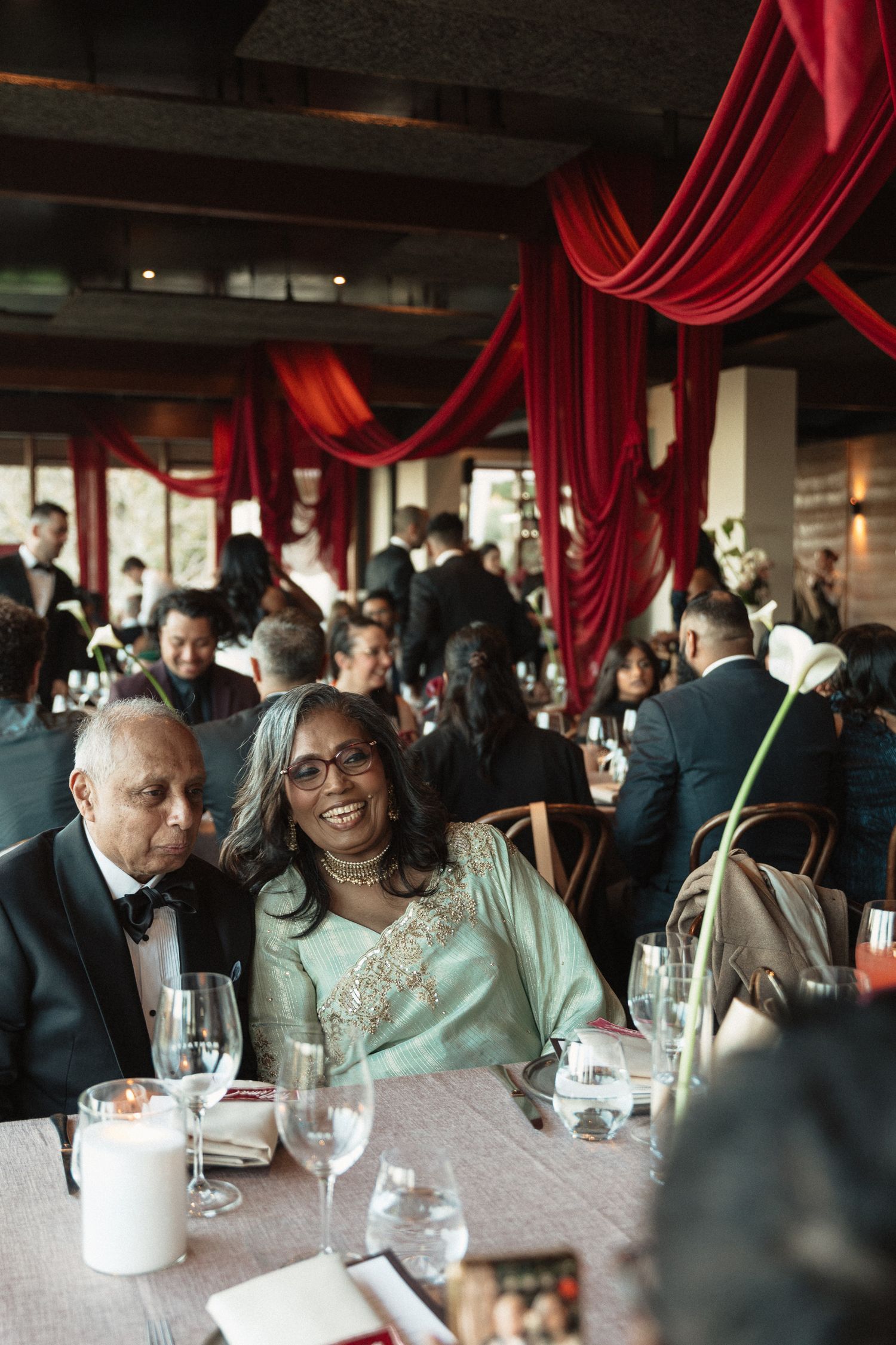 Guests enjoy a formal dining experience under elegant red curtains at an upscale venue.