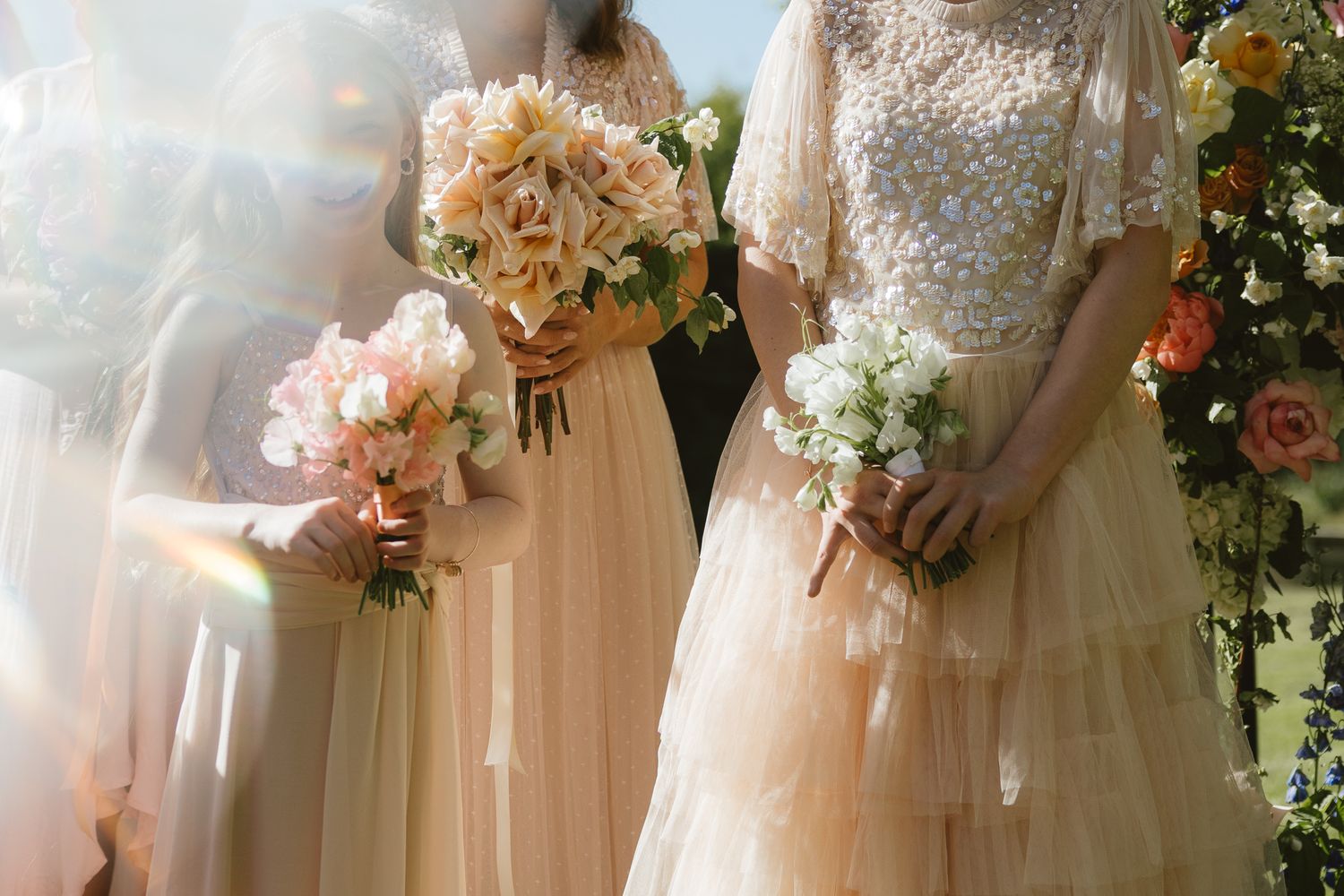 Soft-focus detail of wedding gowns and pastel bouquets in natural light.