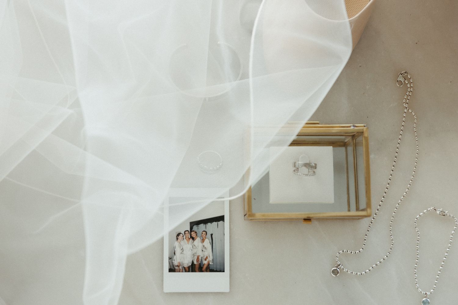 Wedding veil draped elegantly over a polaroid photo and accessories.