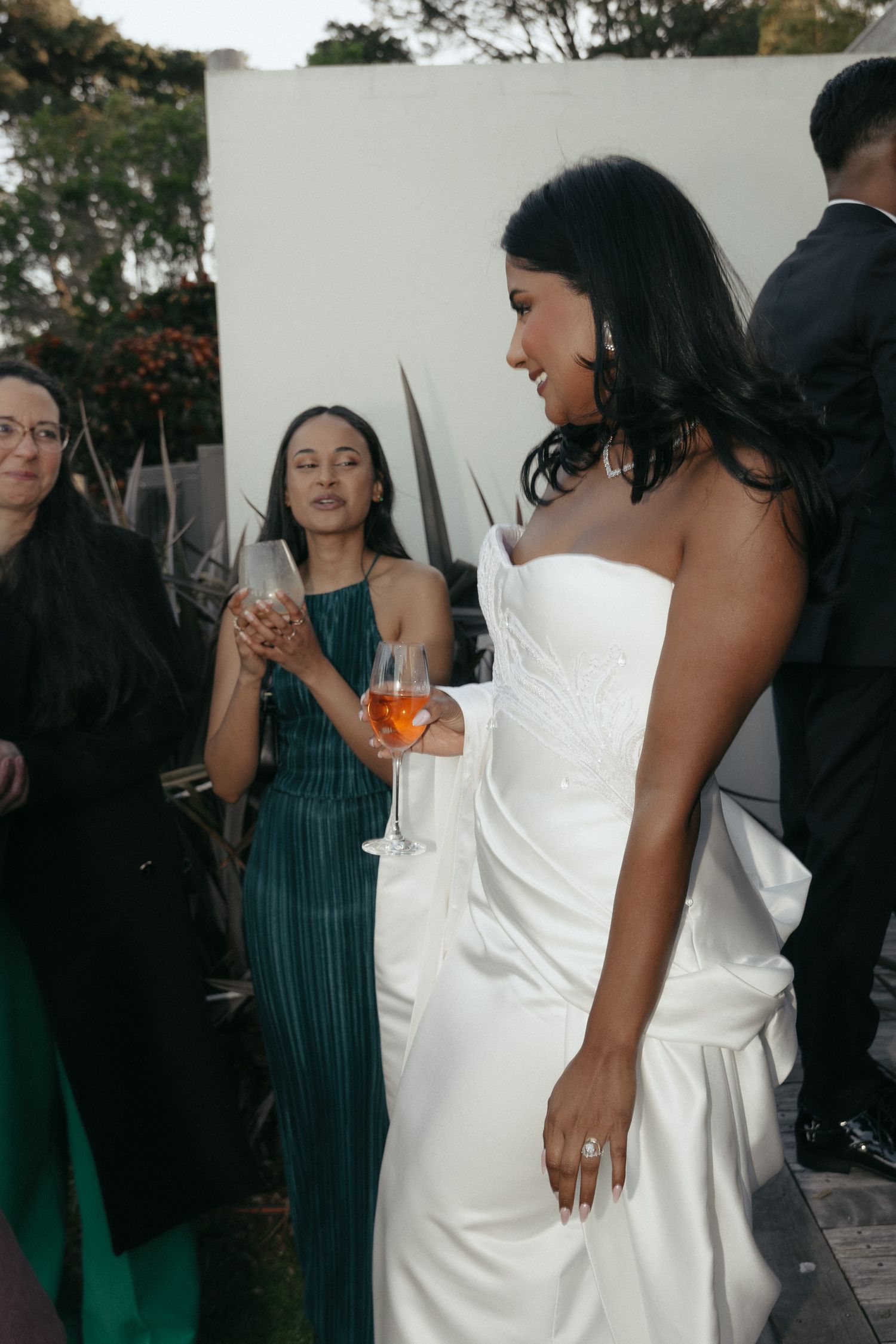 Wedding guests in formal attire gather outdoors for a celebration.