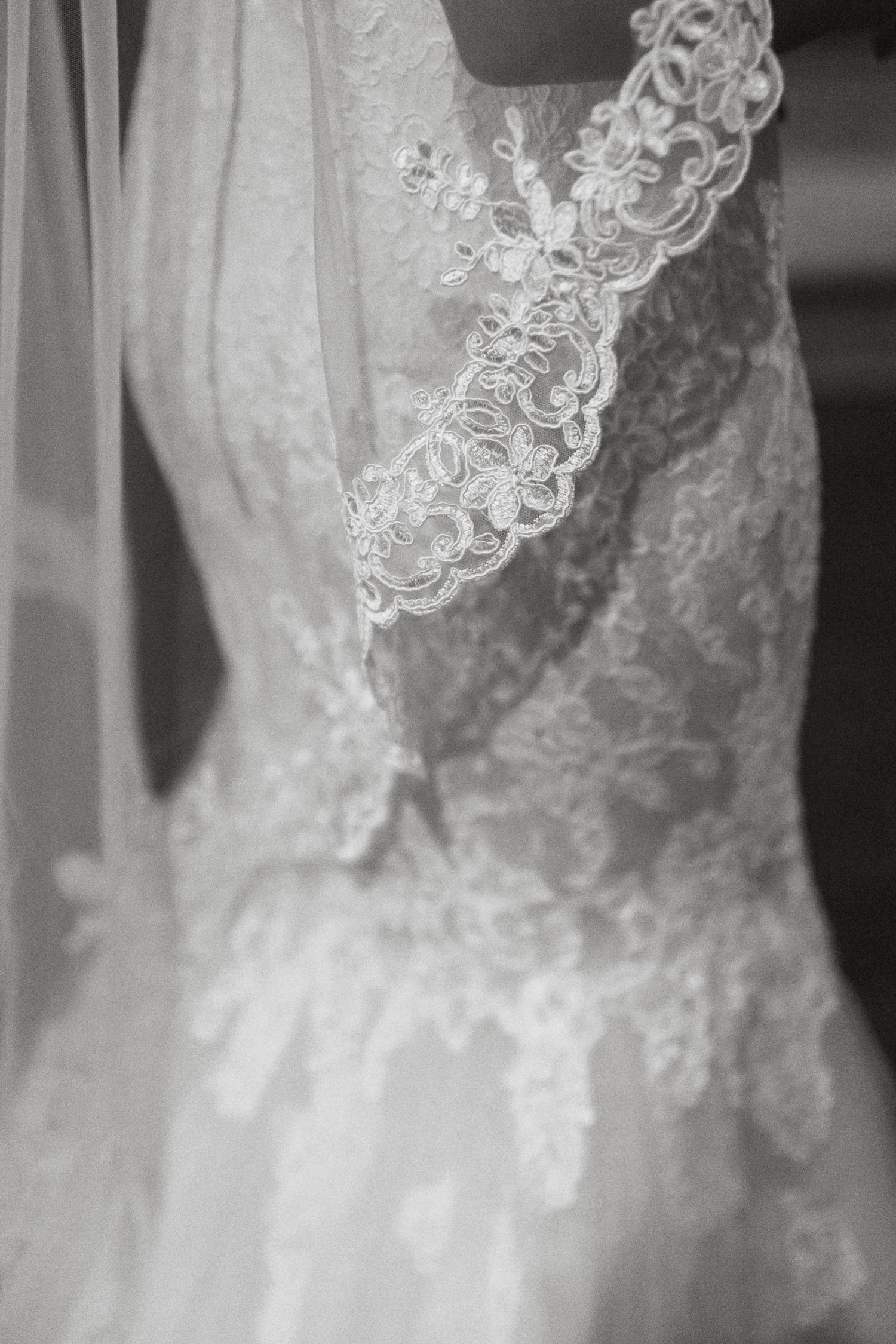 Close-up detail of delicate white lace and embroidery on a wedding dress.