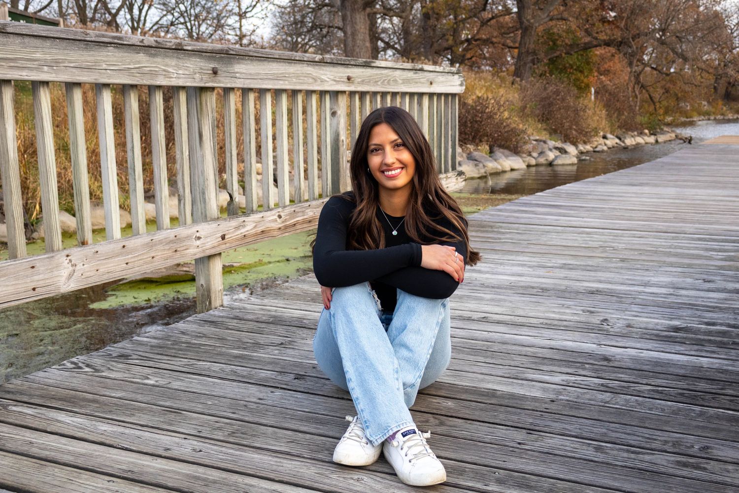 Casual portrait on wooden boardwalk with white railing during fall season.