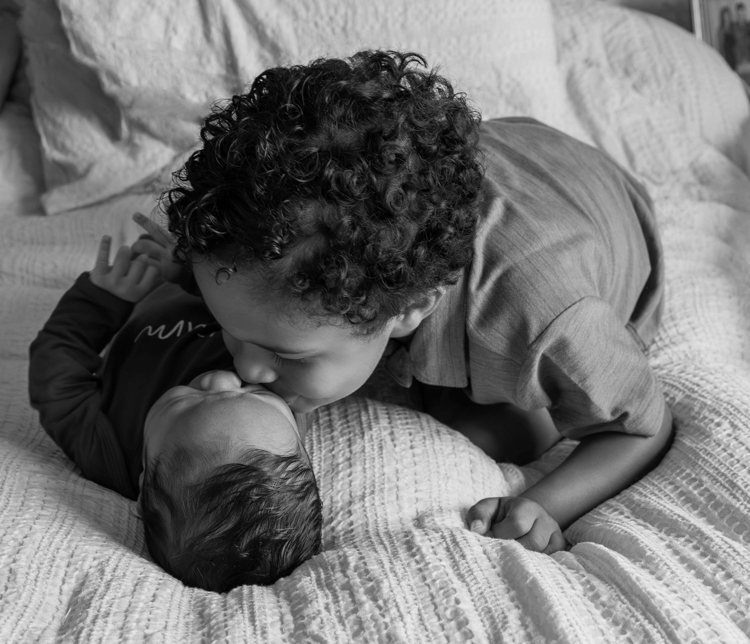 A child with curly hair rests peacefully on the pages of an open book in black and white.