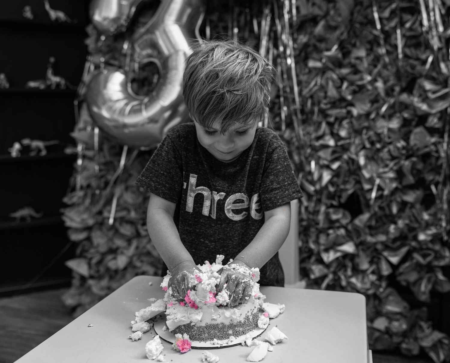 A person smashes their face into a cake on a table while others watch and record the moment on their phones.
