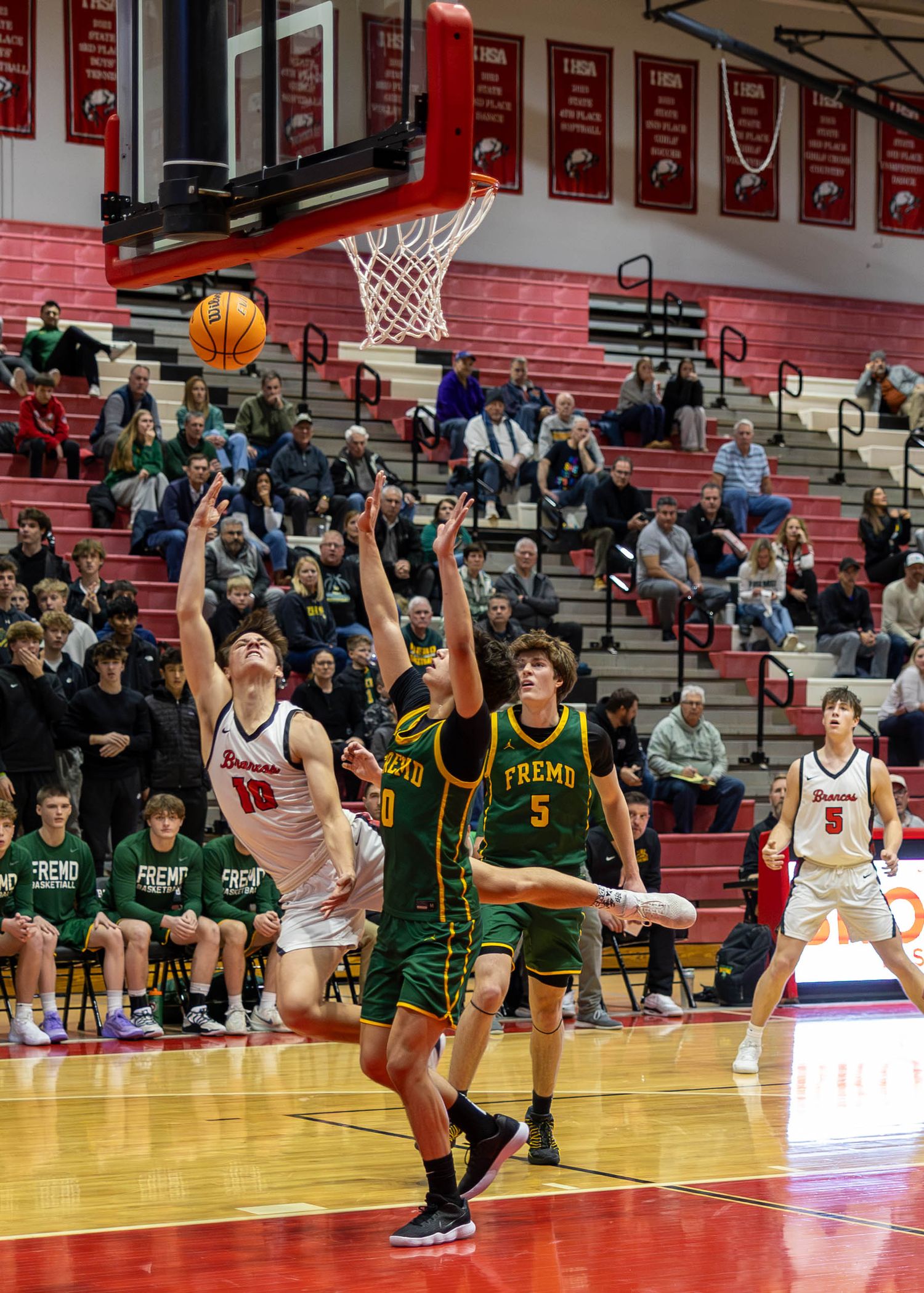 High school basketball player #10 attempts a layup during an intense game against Fremo team in a packed gymnasium.