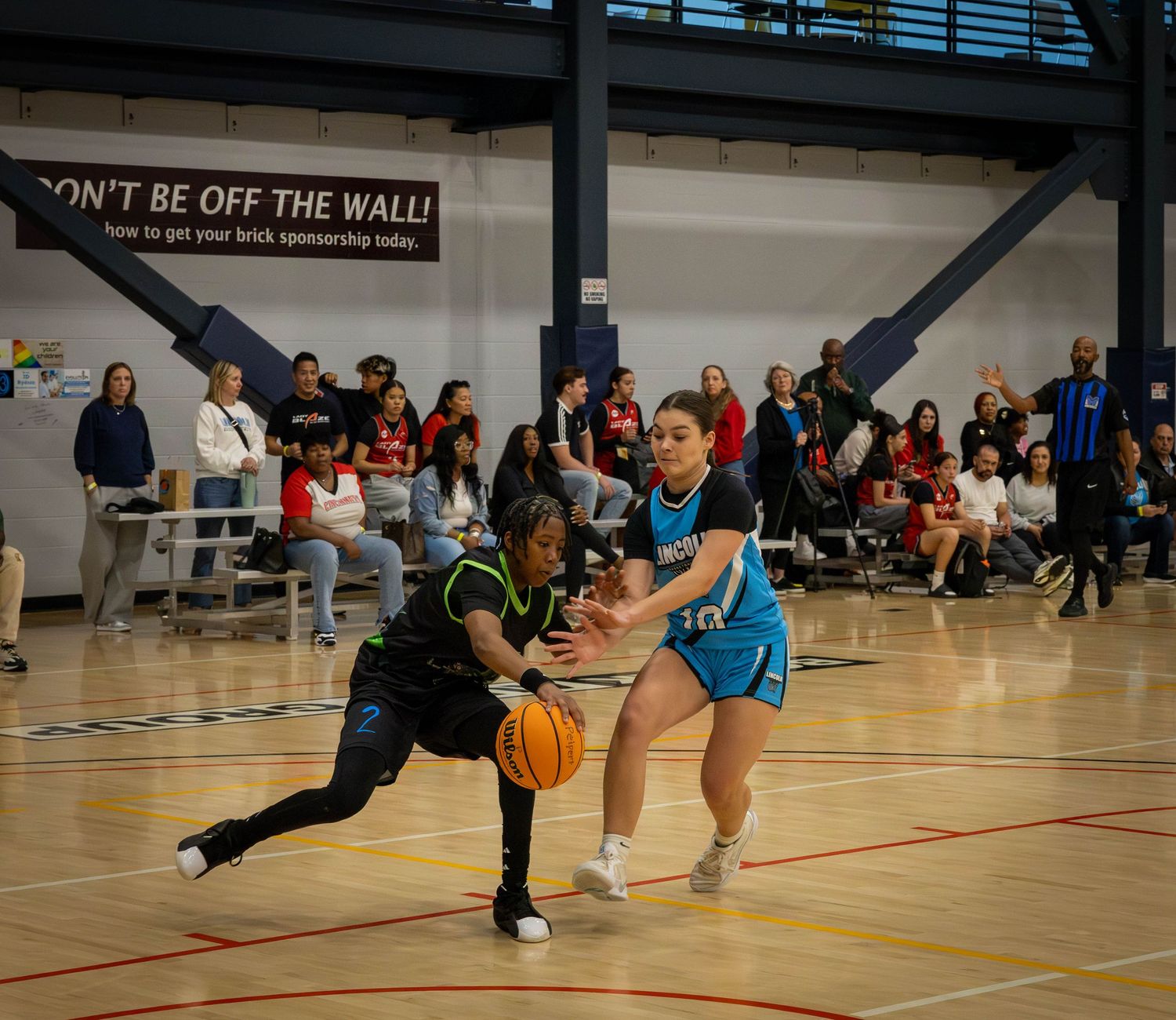 A dodgeball player leaps horizontally through the air while throwing a ball during an indoor gym game.