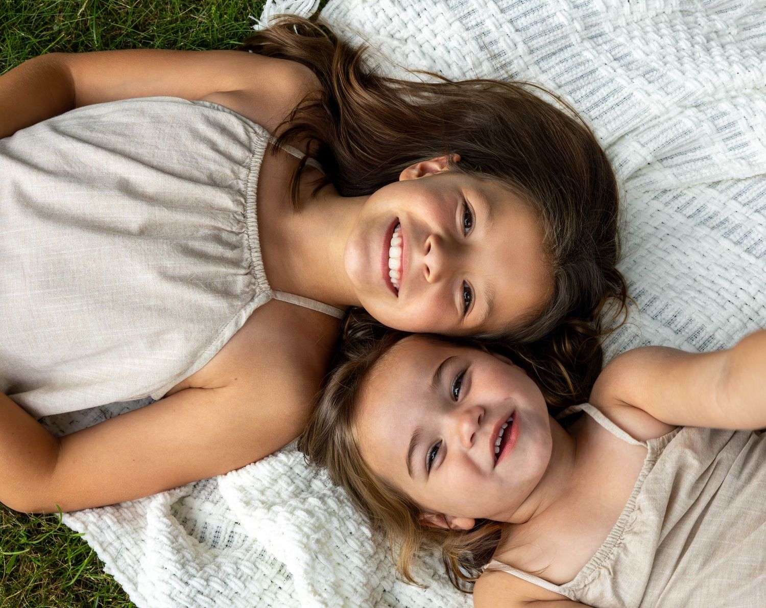 Two people laying down on a white blanket while smiling and sharing a joyful moment together.