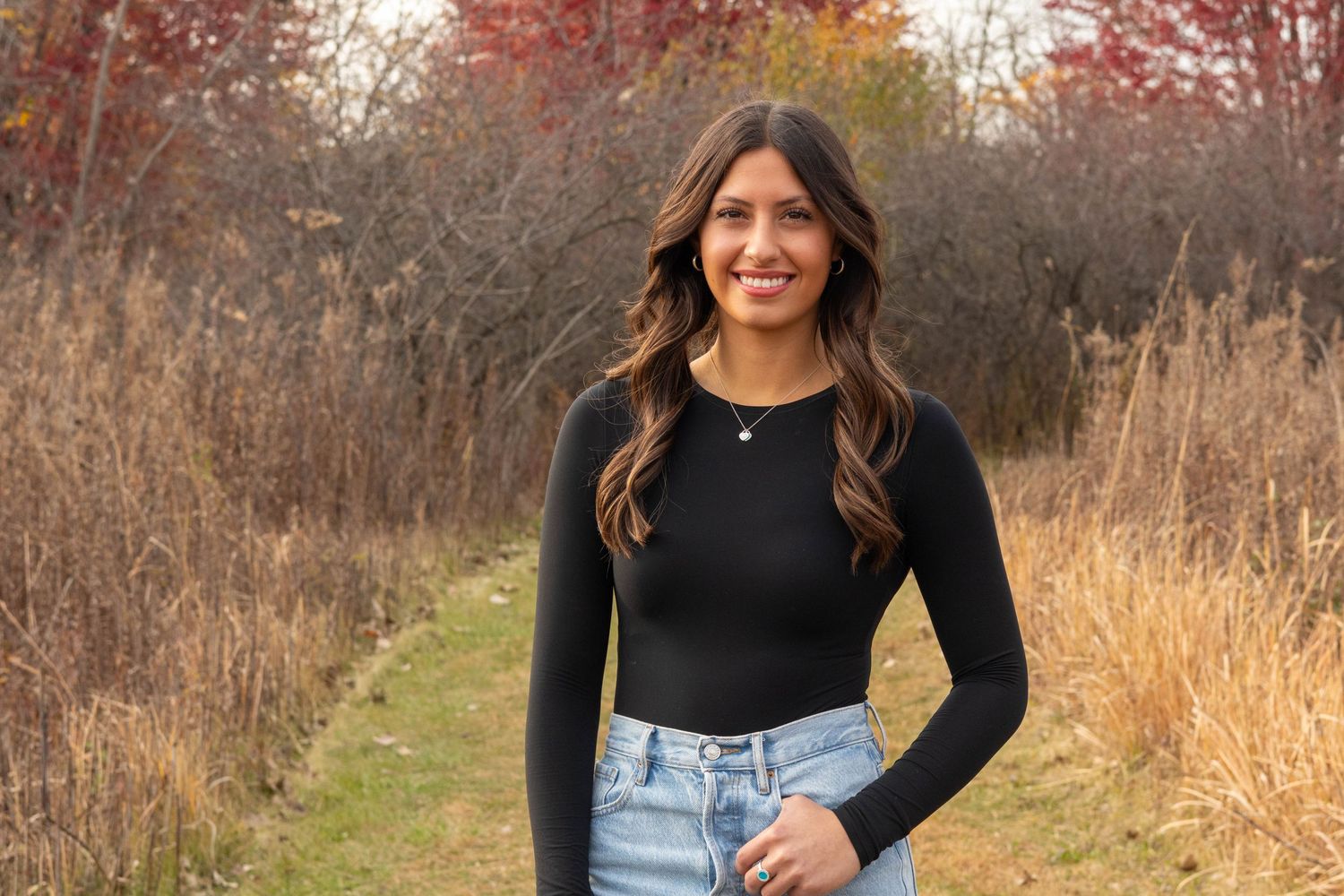 Outdoor portrait in autumn field with golden grass and fall colors.