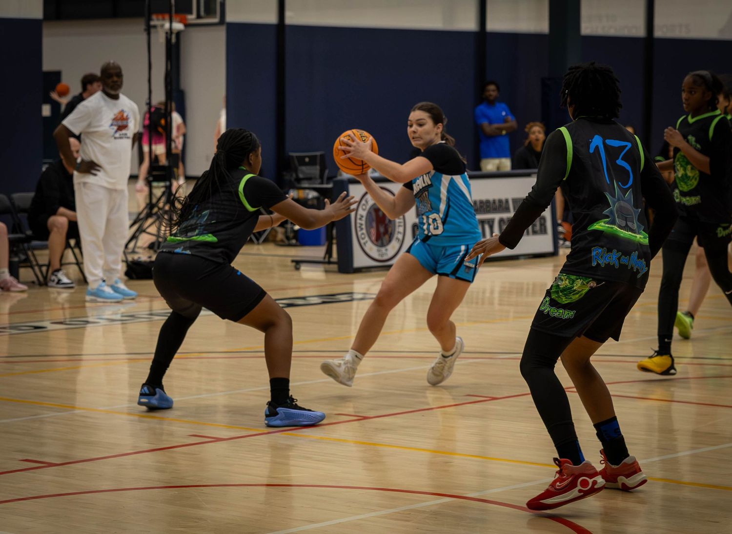 Players compete in an indoor basketball game on a wooden court with vibrant neon uniforms and shoes.