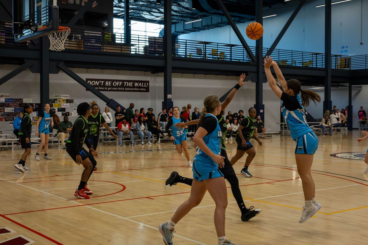 Basketball players compete on an indoor court during an intense game with multiple players in action.