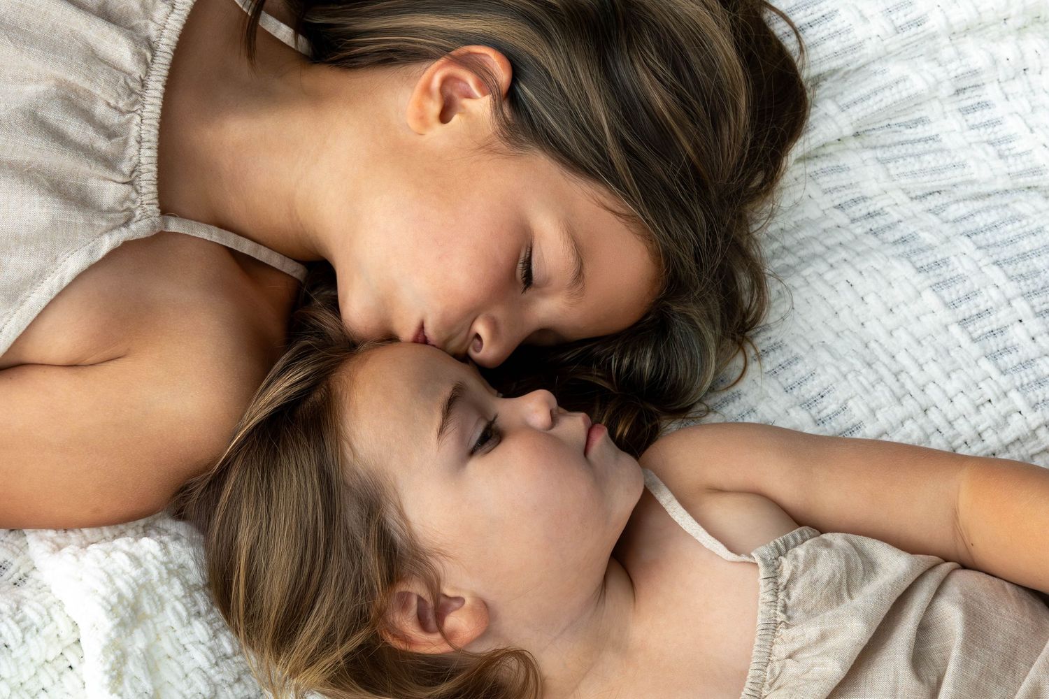 A series of tender romantic moments between a couple lying together on white bedding.