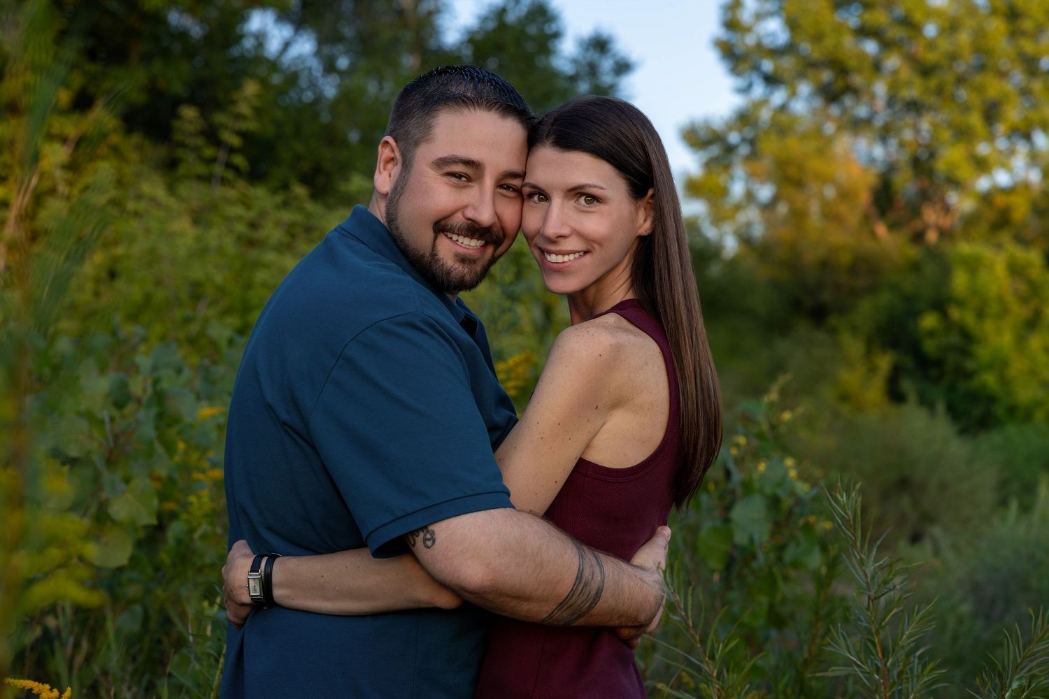 A couple shares tender moments together in a lush outdoor setting during golden hour.