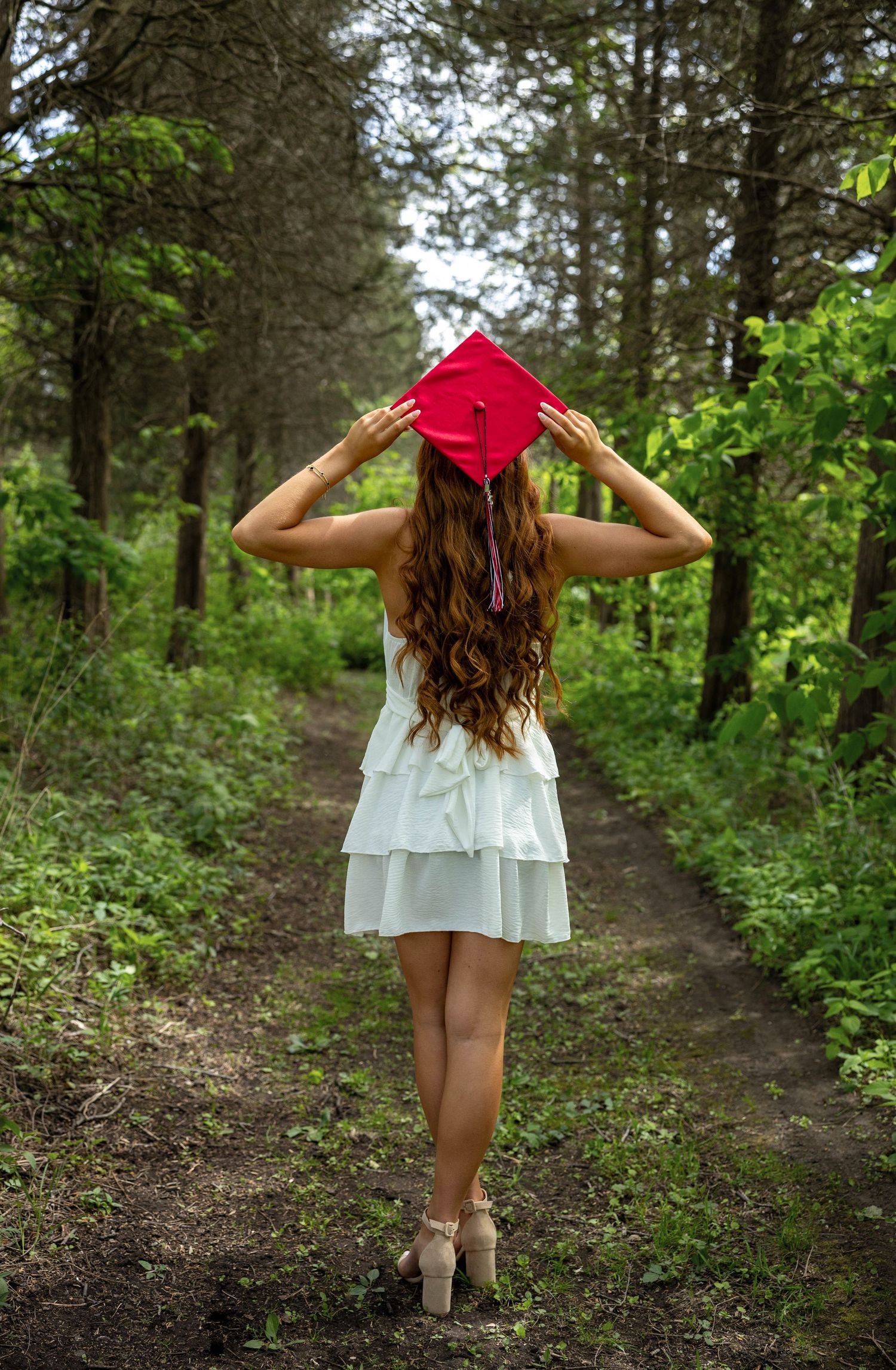 A figure in a white dress and red hat walking along a forested trail, shown from three different angles.