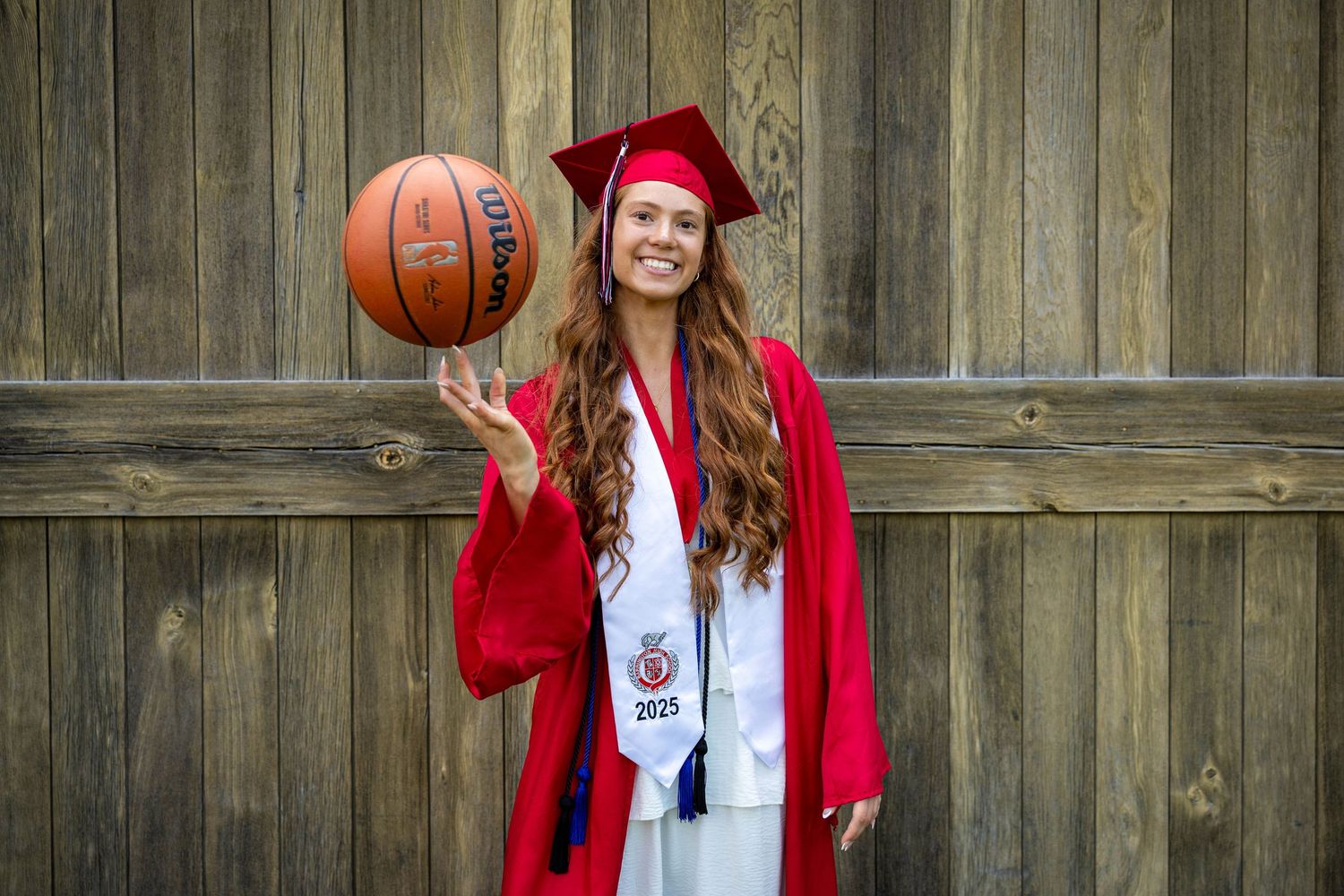 Series of graduation portraits with someone in red cap and gown holding a basketball against wooden fence backdrop.