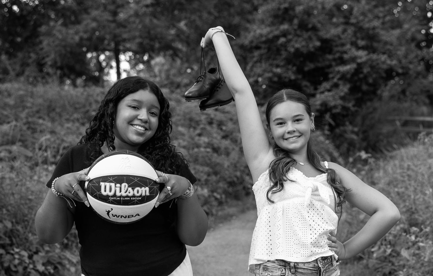 Two students pose outdoors with a Wilson basketball in this black and white portrait.