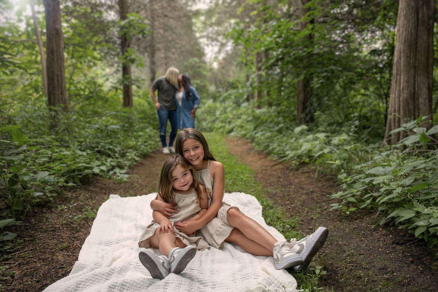 People share intimate moments while relaxing on a blanket in a peaceful wooded area.
