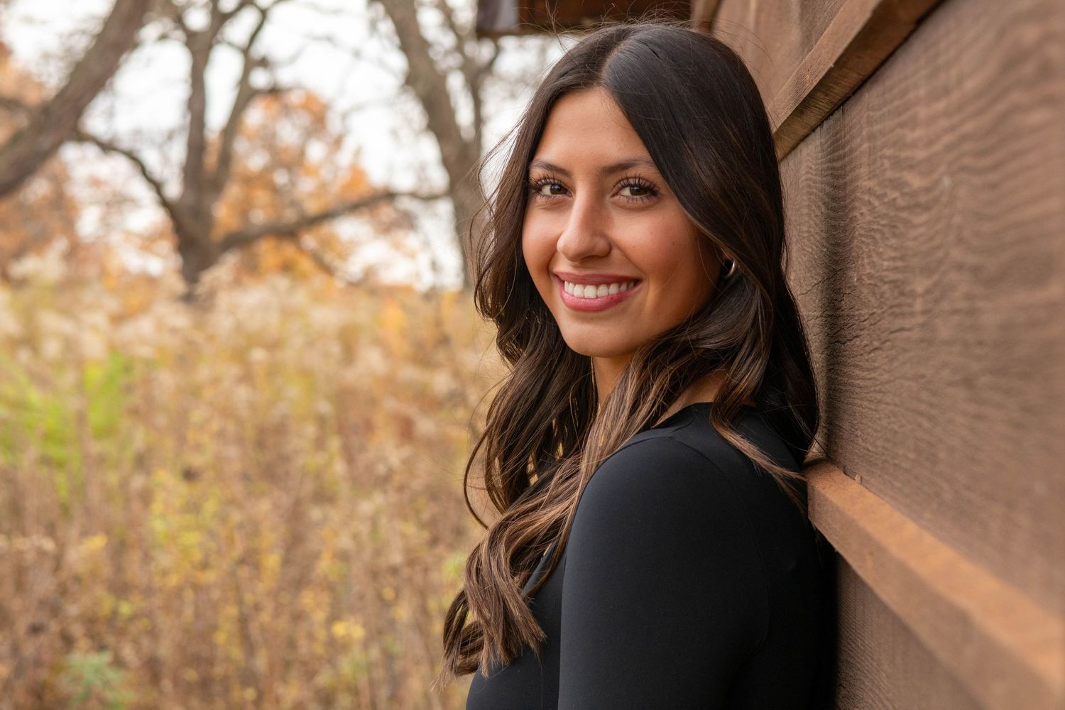 Autumn portrait against wooden wall with natural fall colors in background.