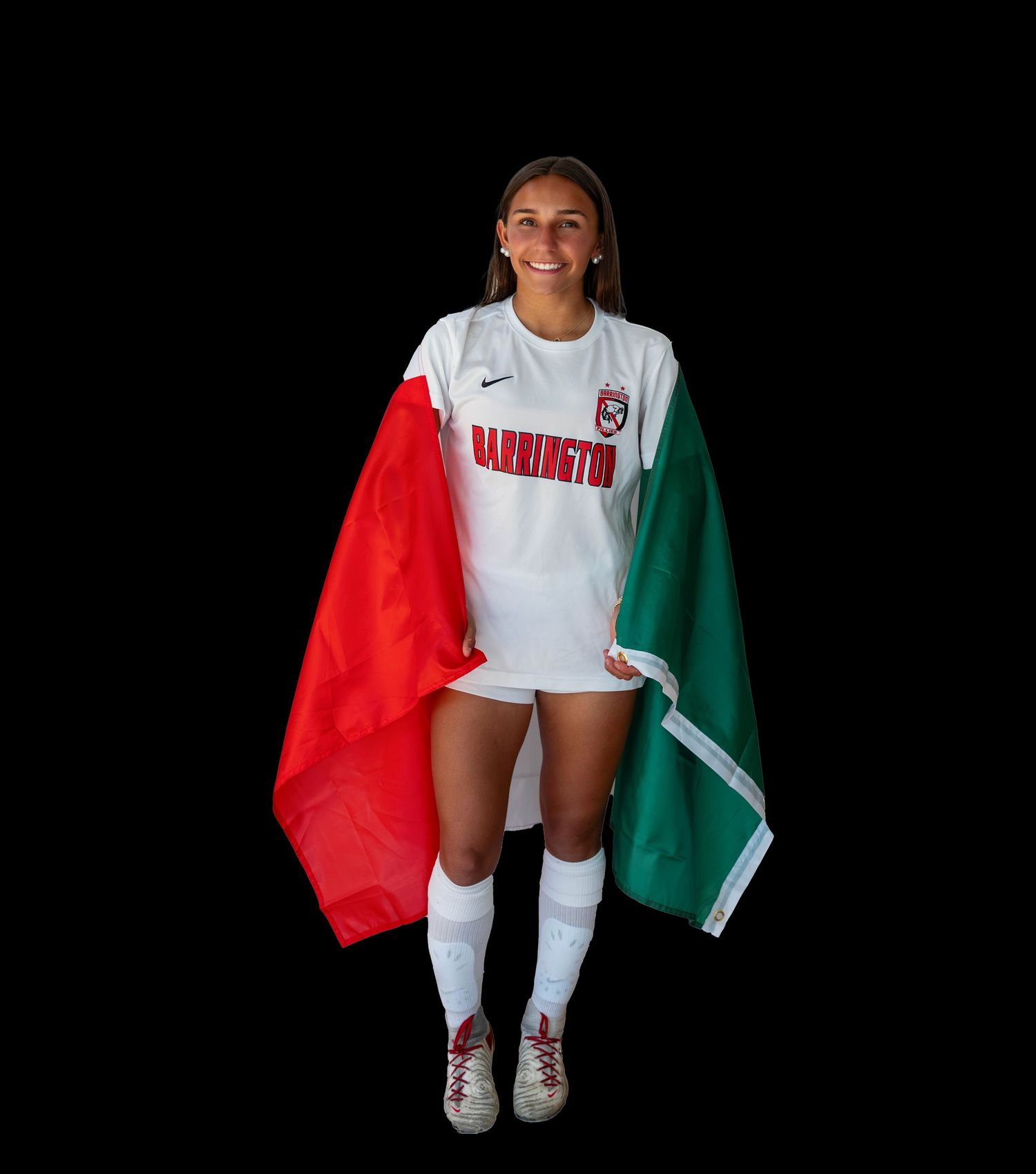 An athlete stands in front of a black backdrop wearing a white uniform and draped in red and green national team colors.