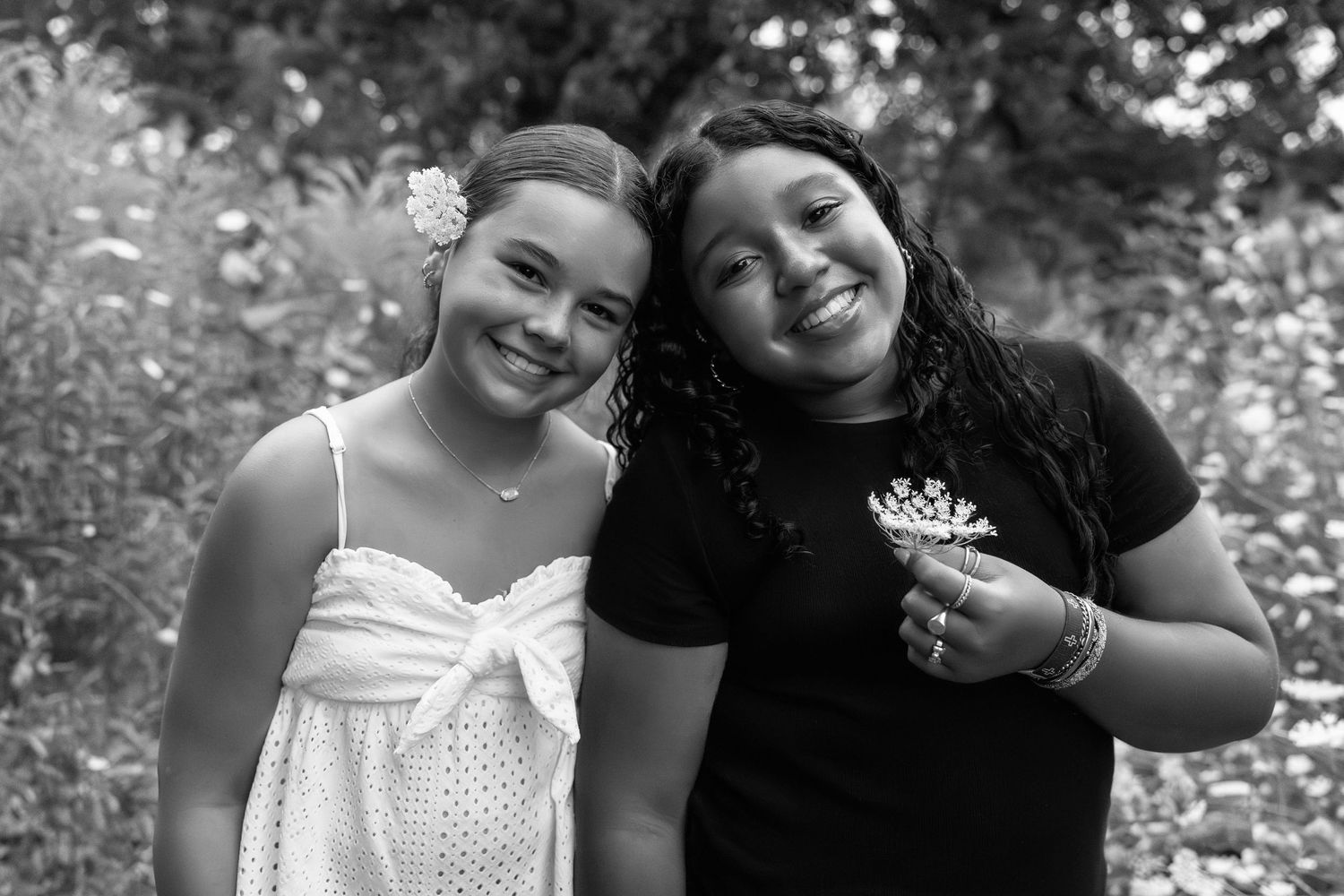 Black and white photo of people smiling together and embracing in an outdoor setting.