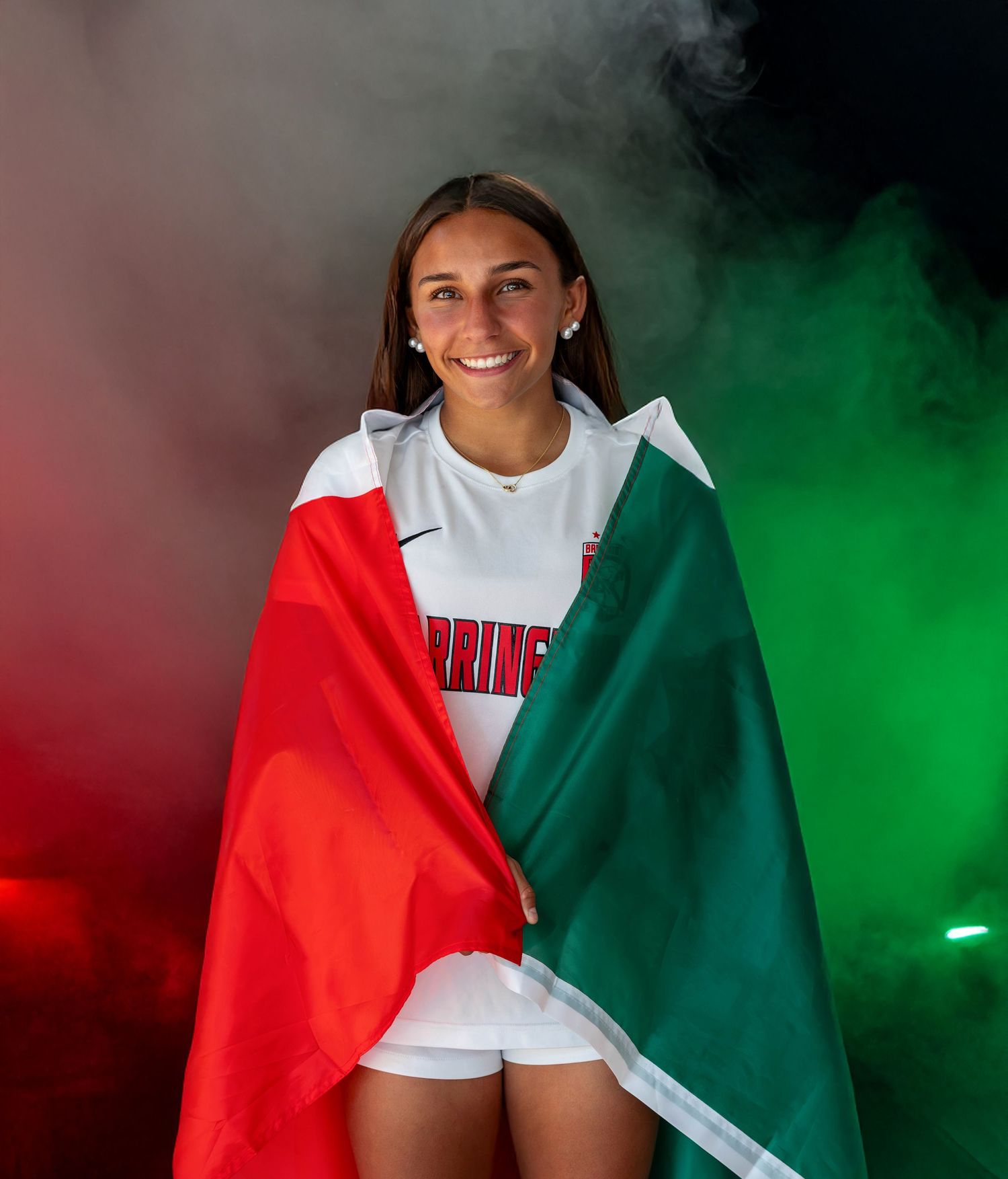 Athlete in red jacket and white uniform poses with Mexico flag against dramatic red and green lighting effects.